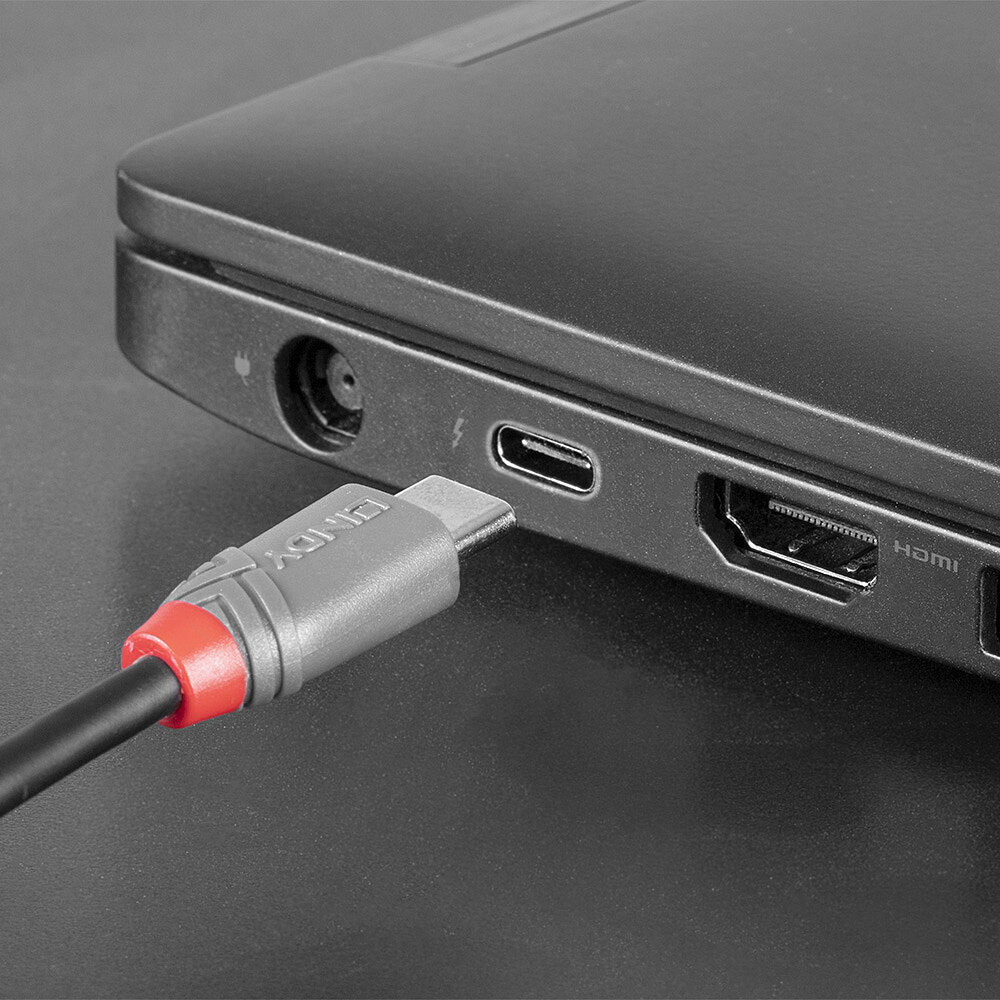 Un cavo USB-C nero è collegato a un laptop. Sono visibili una porta HDMI e una porta di alimentazione.
