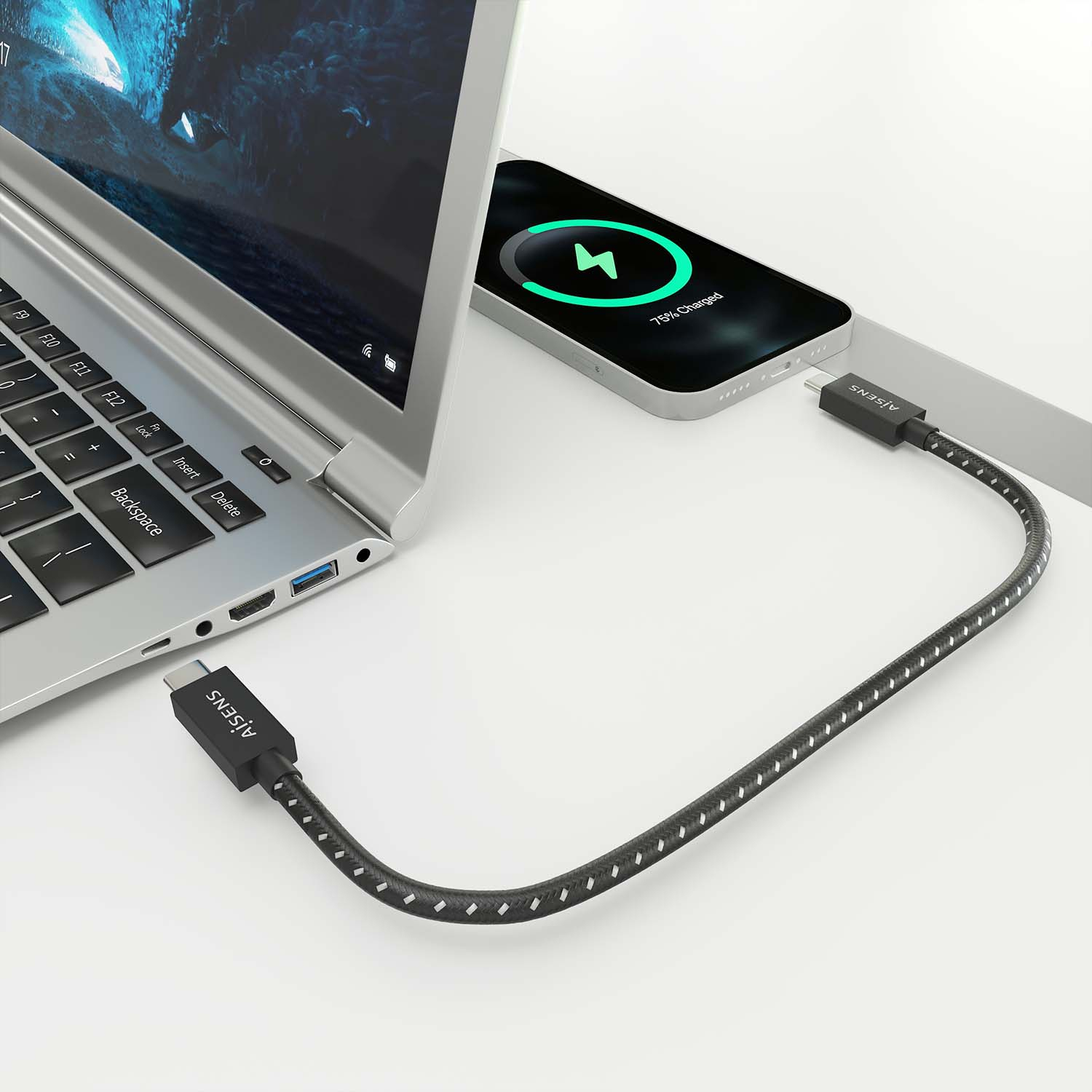 Laptop che carica un telefono con un cavo USB-C nero. Il telefono mostra il 75% di carica, sfondo bianco.