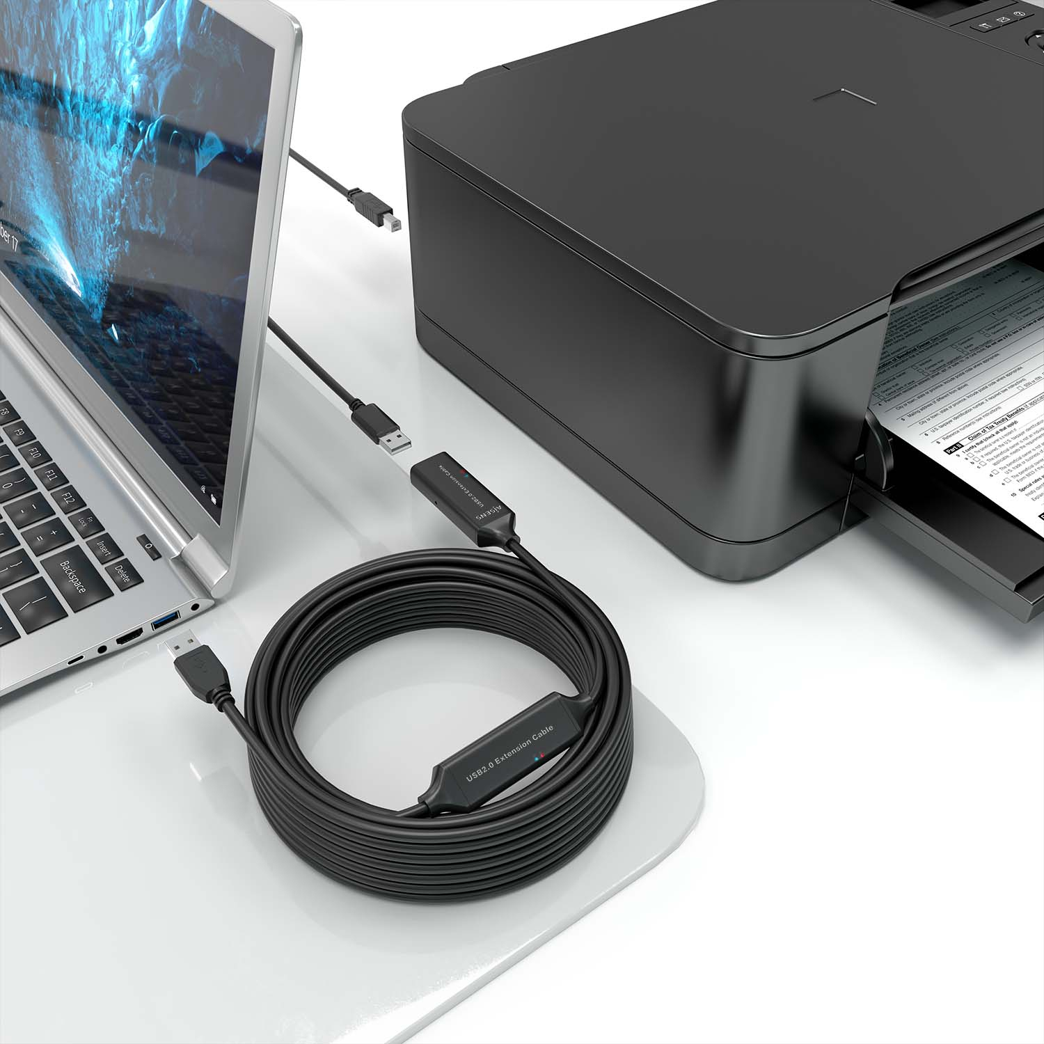 Un laptop e una stampante collegati da cavi USB neri. I cavi sono su una superficie bianca.