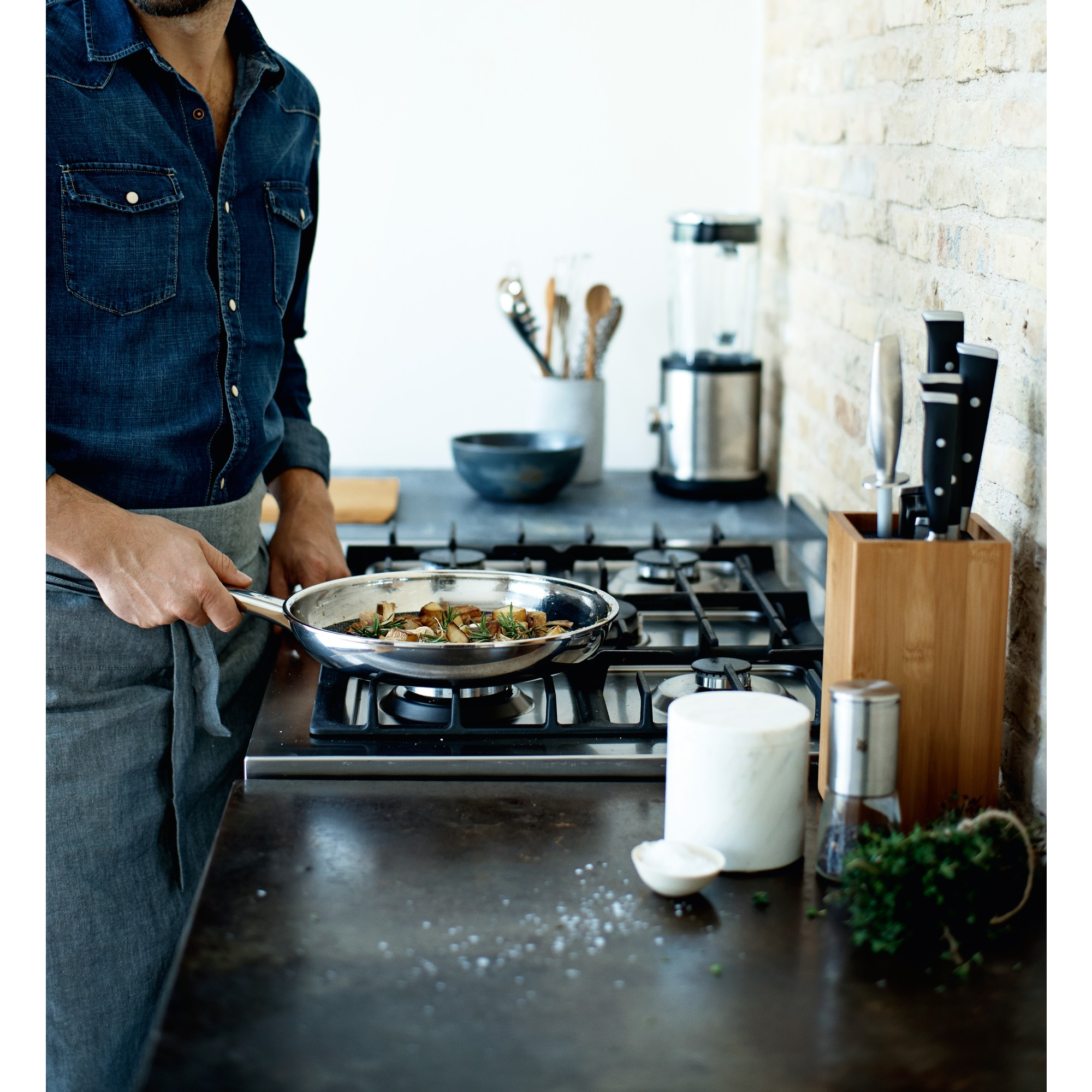 Mężczyzna gotuje grzyby na patelni na kuchence w kuchni.