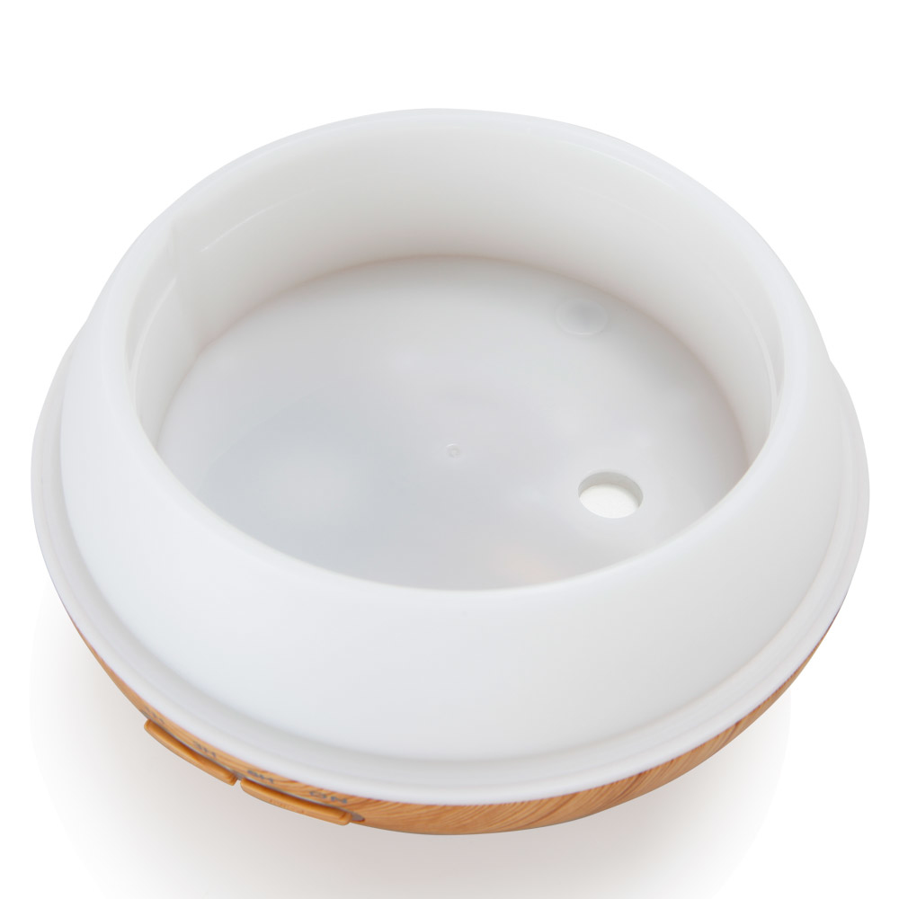 Wnętrze białego nawilżacza. Brązowa podstawa imitująca drewno. Białe tło.