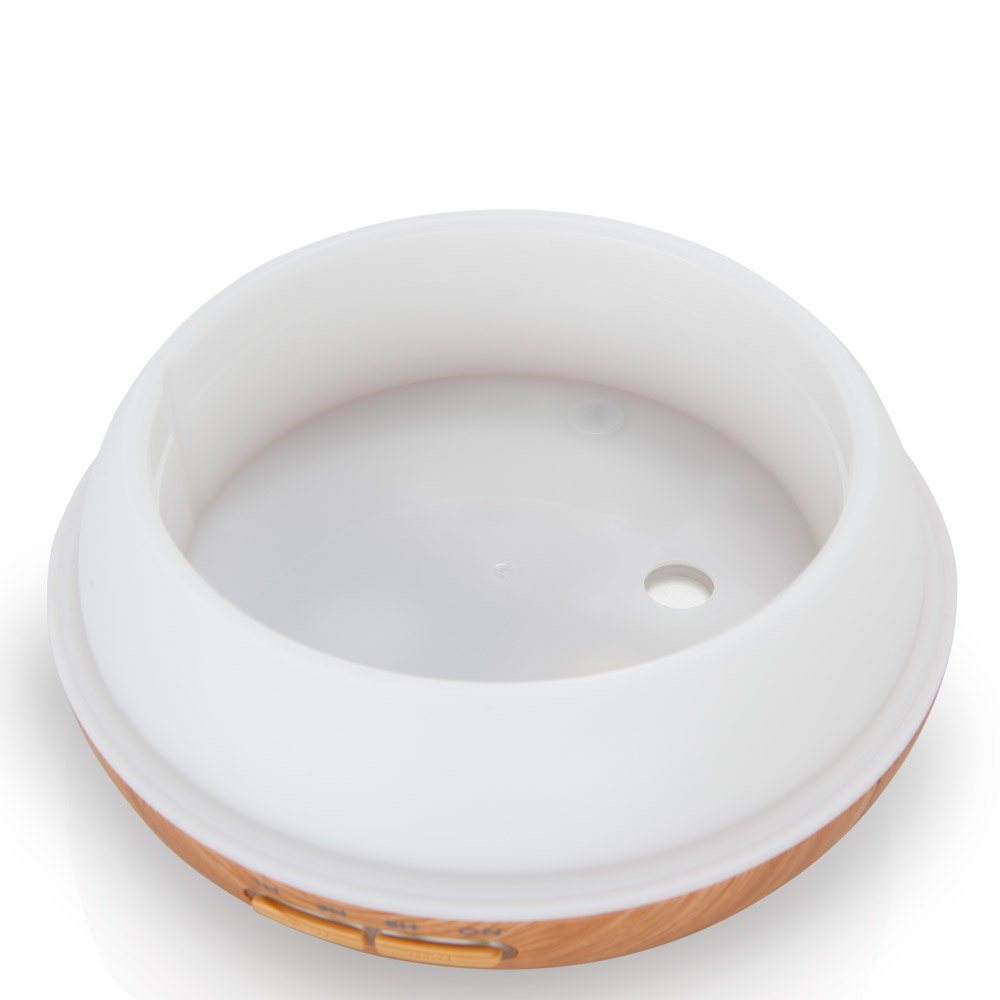 Biały dyfuzor olejków eterycznych. Ma jasną drewnianą podstawę i biały wierzch. Wnętrze jest widoczne.