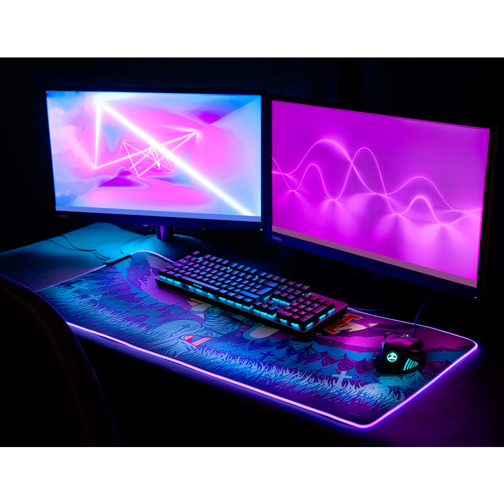 Gaming-Setup mit zwei Monitoren, Tastatur, Maus und Mauspad mit Lichtern, schwarzer Tisch.