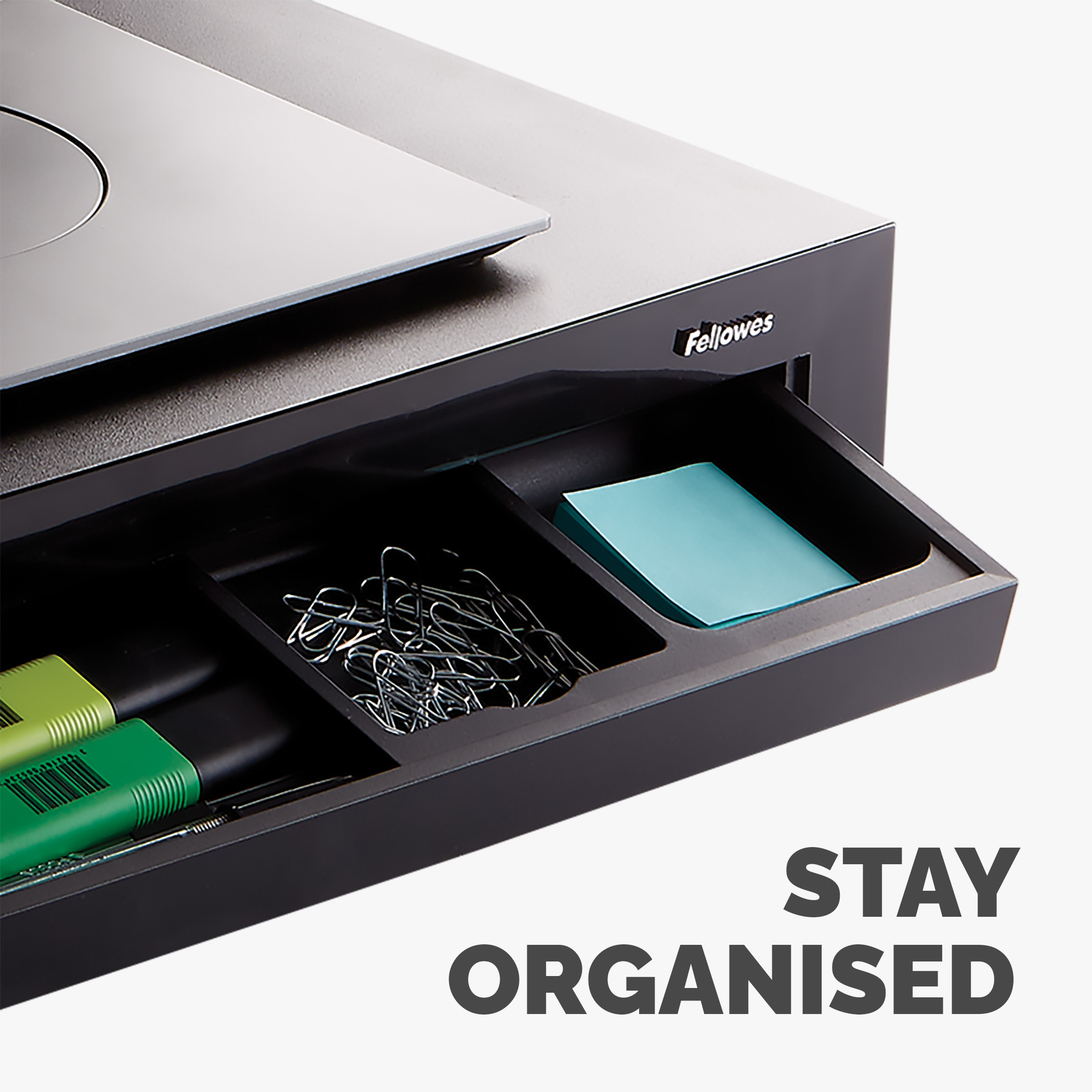 Czarna szuflada biurka z artykułami biurowymi. Tekst: 'Bądź zorganizowany'.