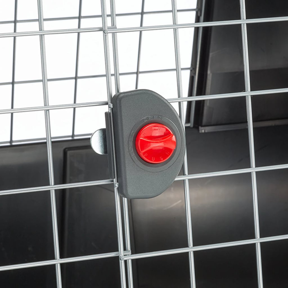Zatrzask drzwi klatki dla psa z czerwonym przyciskiem i metalowym drutem.