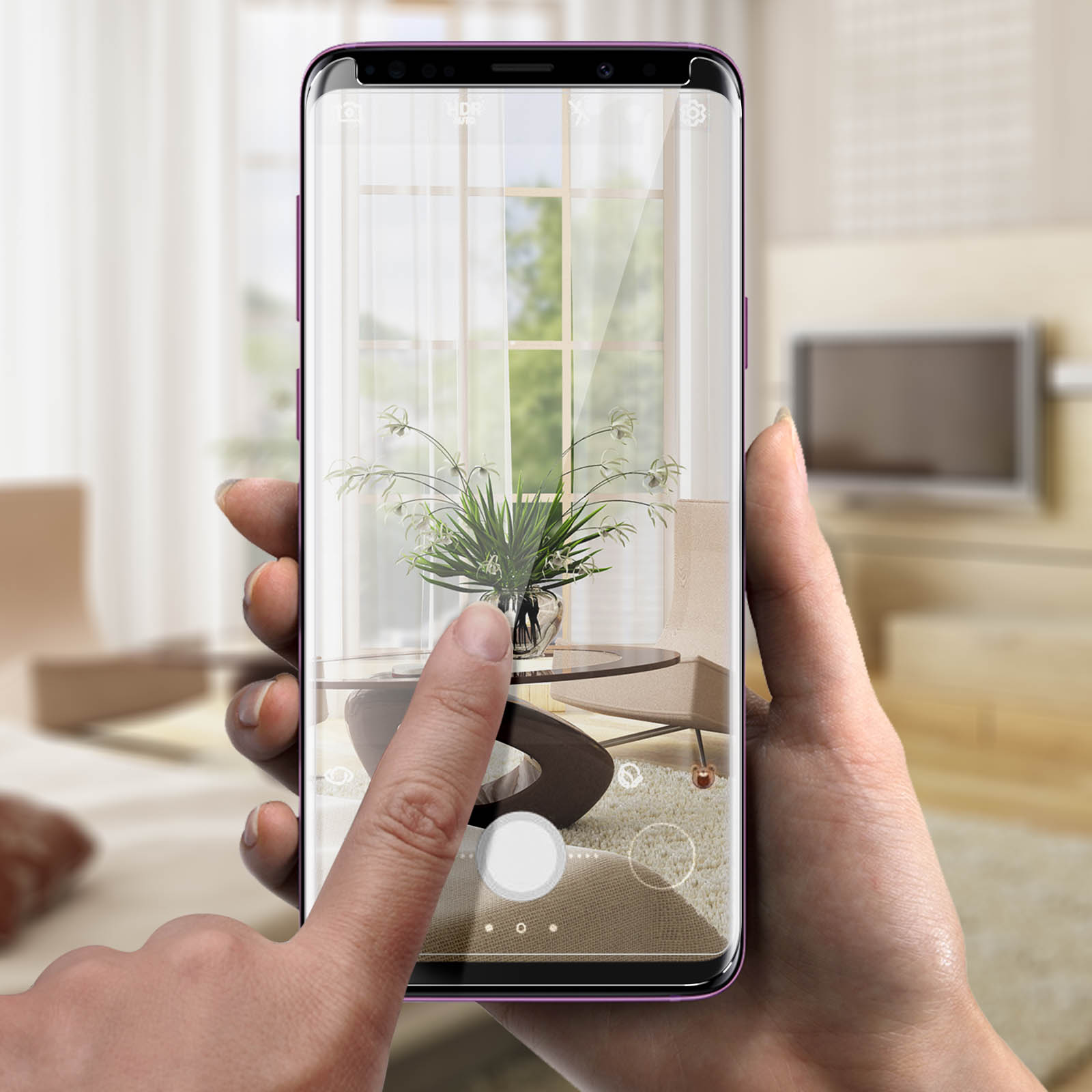 Mani che tengono uno smartphone, mostrando una scena con piante in un vaso.