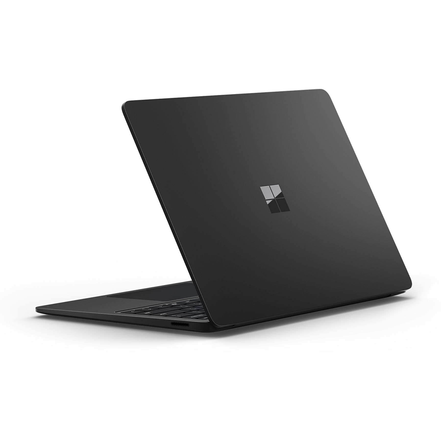 Un laptop nero con il logo Microsoft sul retro, leggermente aperto su una superficie bianca.