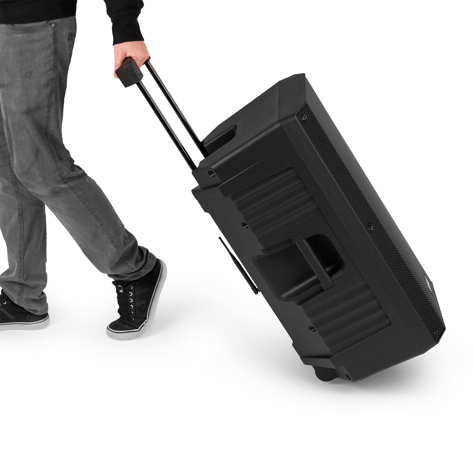 Een persoon die een grote zwarte luidspreker op wielen trekt. Witte achtergrond.