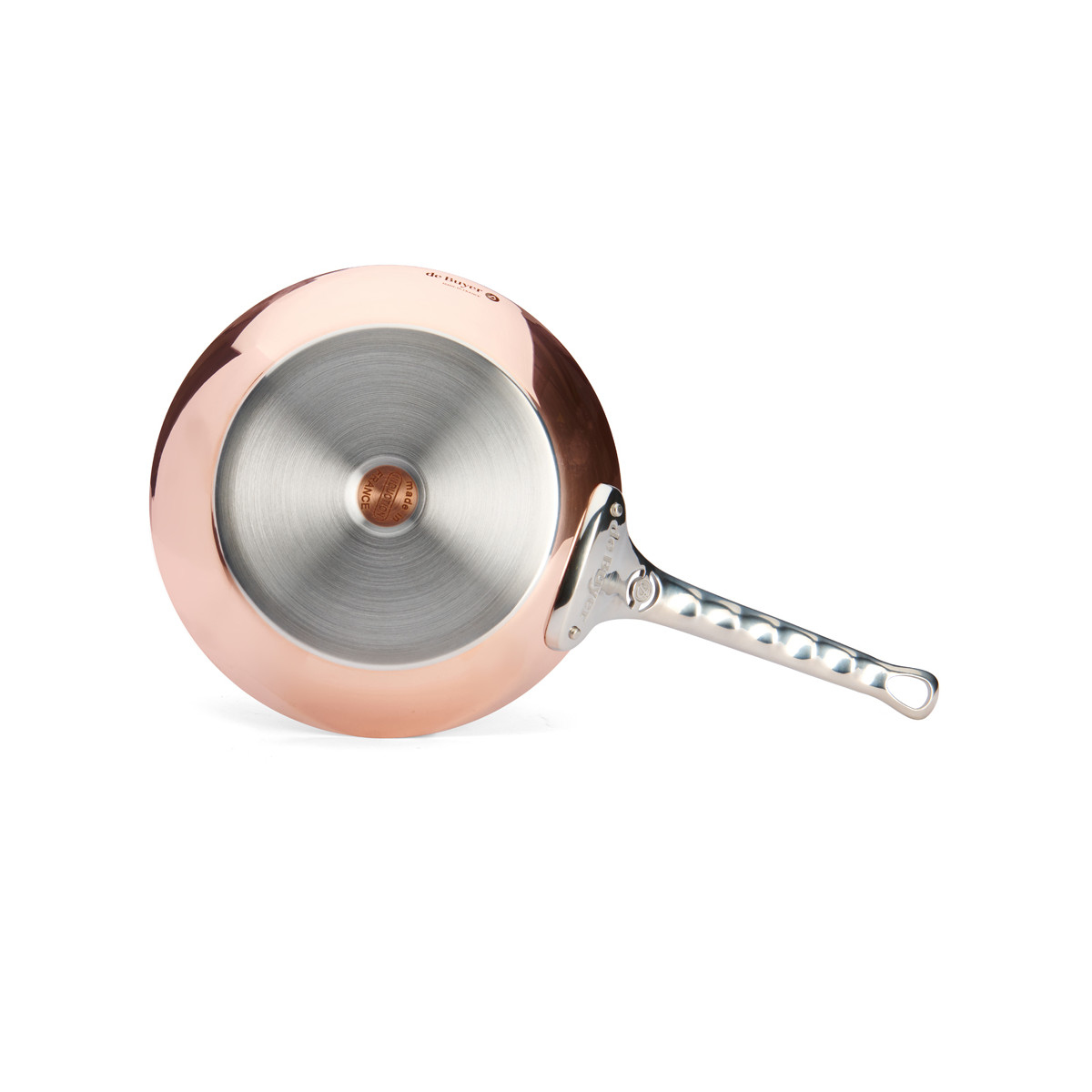 Miedziana patelnia pokazana od spodu. Ma srebrną rączkę i błyszczące wnętrze.