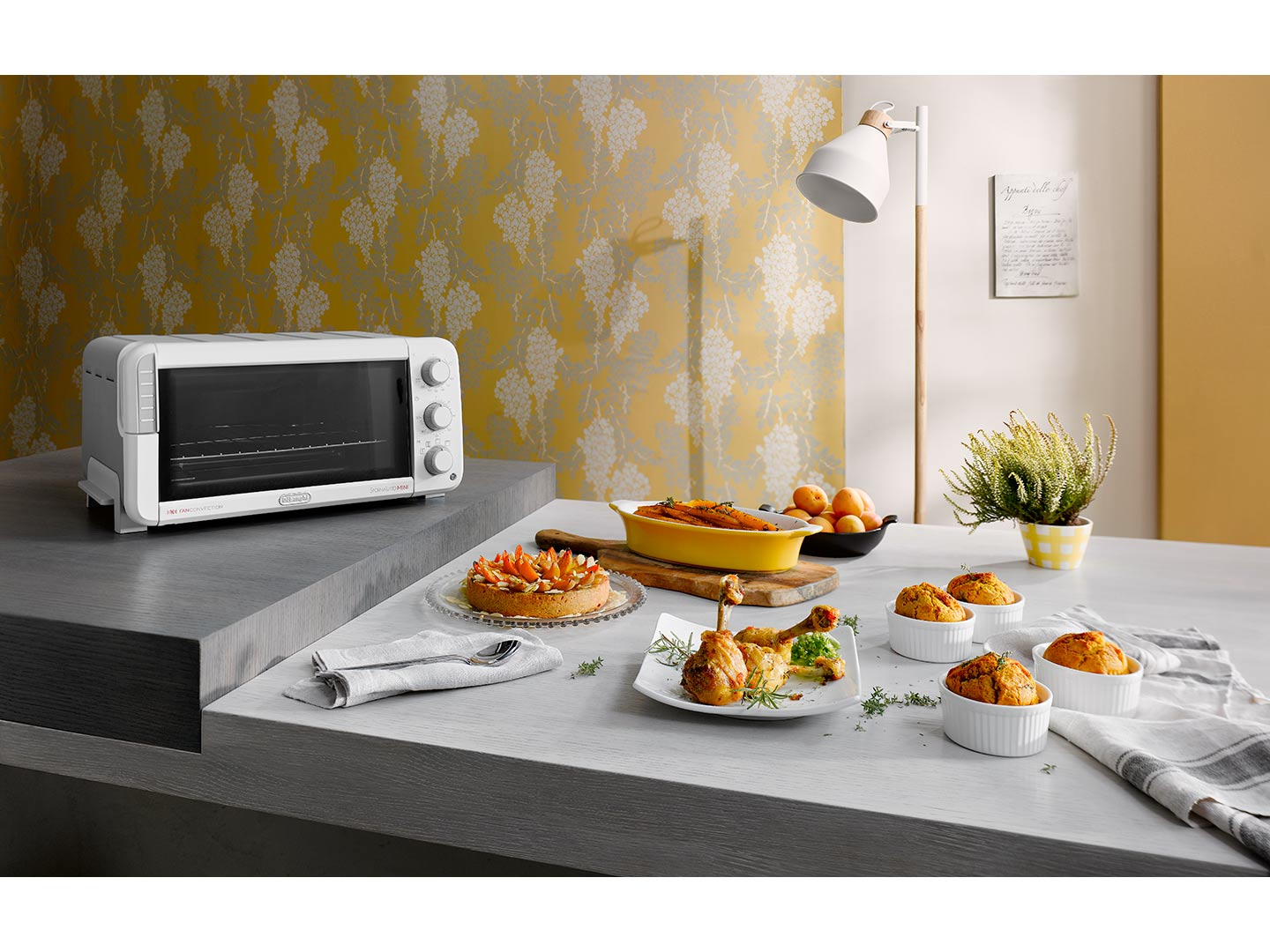 Una escena de cocina con comida en una mesa y un horno blanco.