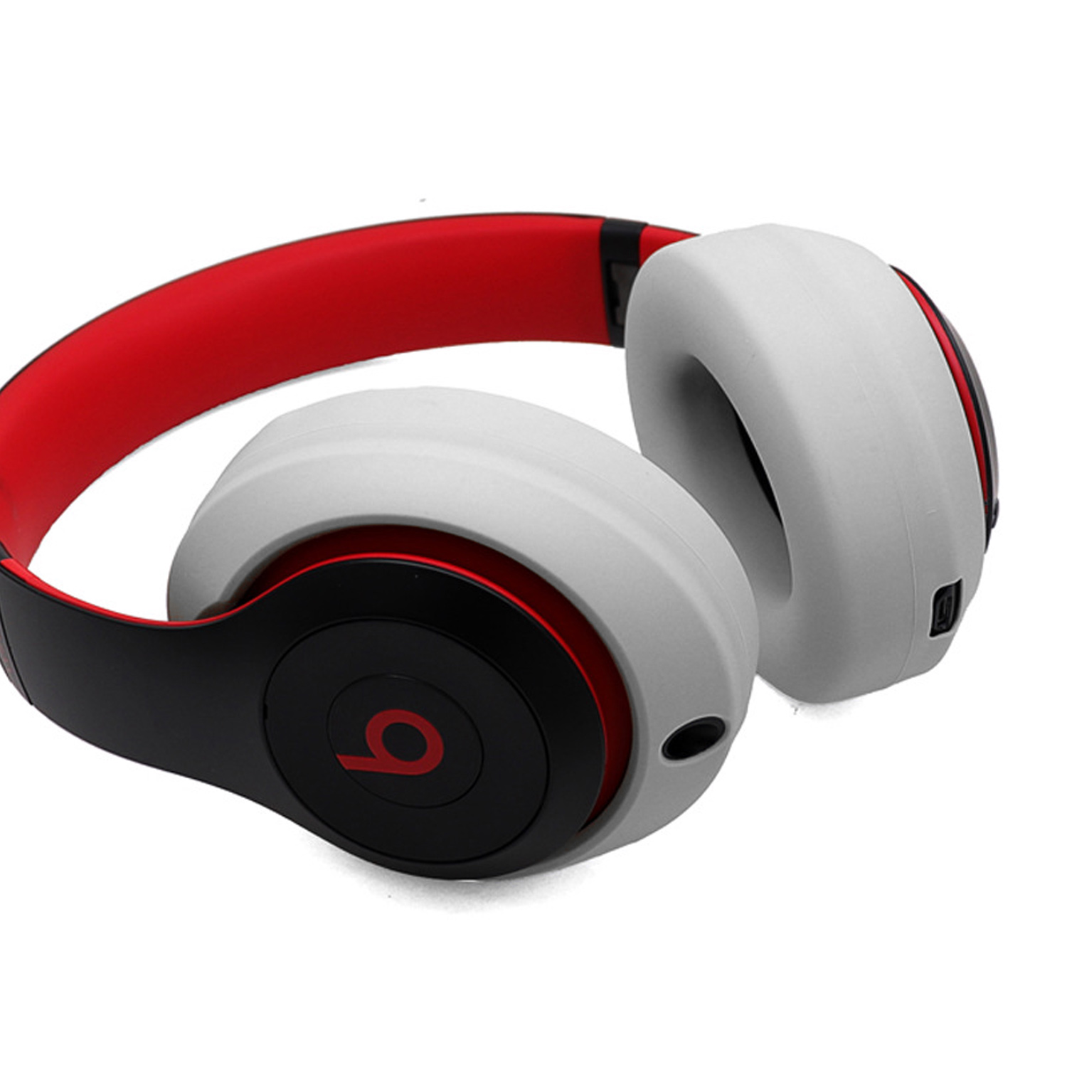 Beats-Kopfhörer, weiße Ohrmuscheln, rotes Stirnband. Schwarze Akzente auf den Ohrmuscheln. Beats-Logo an der Seite.