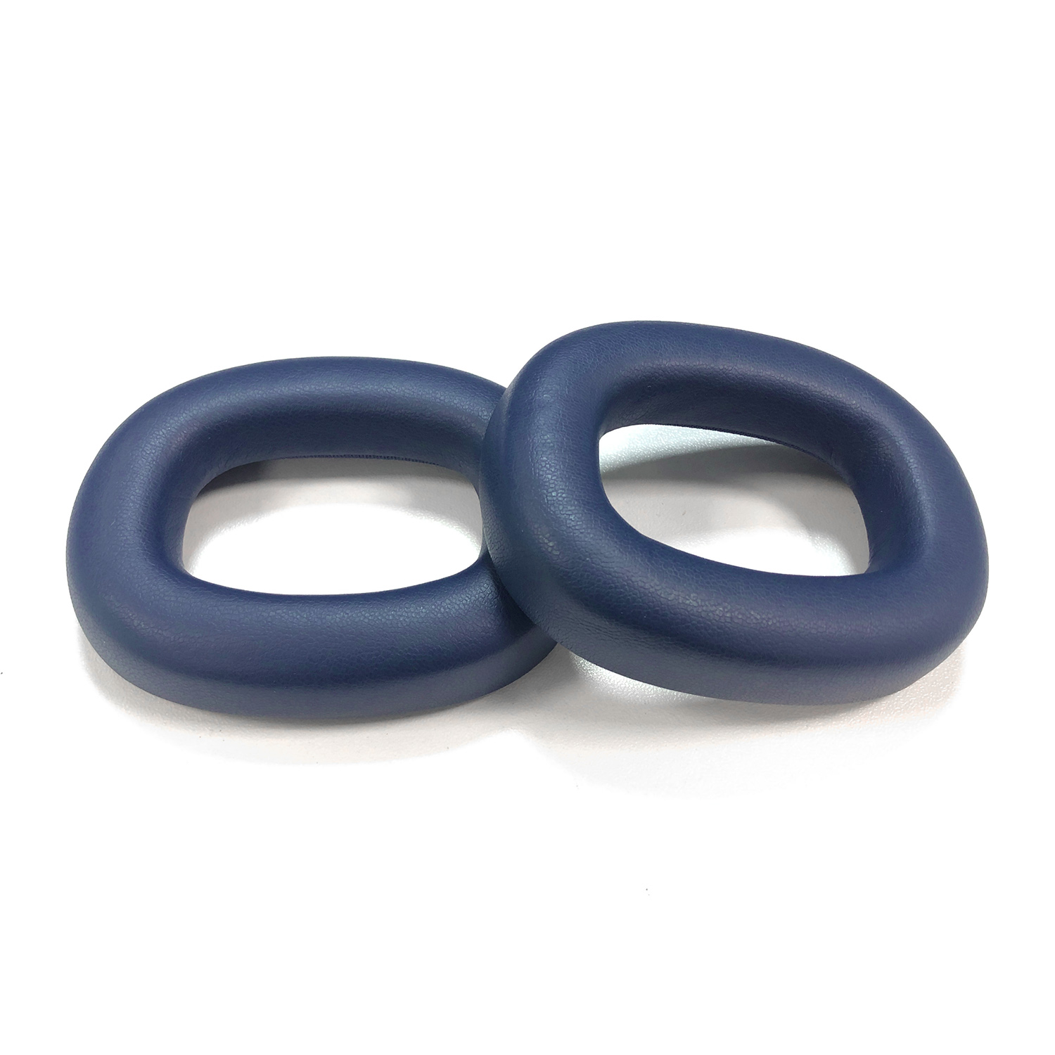 Dwie niebieskie, owalne poduszki na uszy, obok siebie, na białym tle. Poduszki są gładkie.