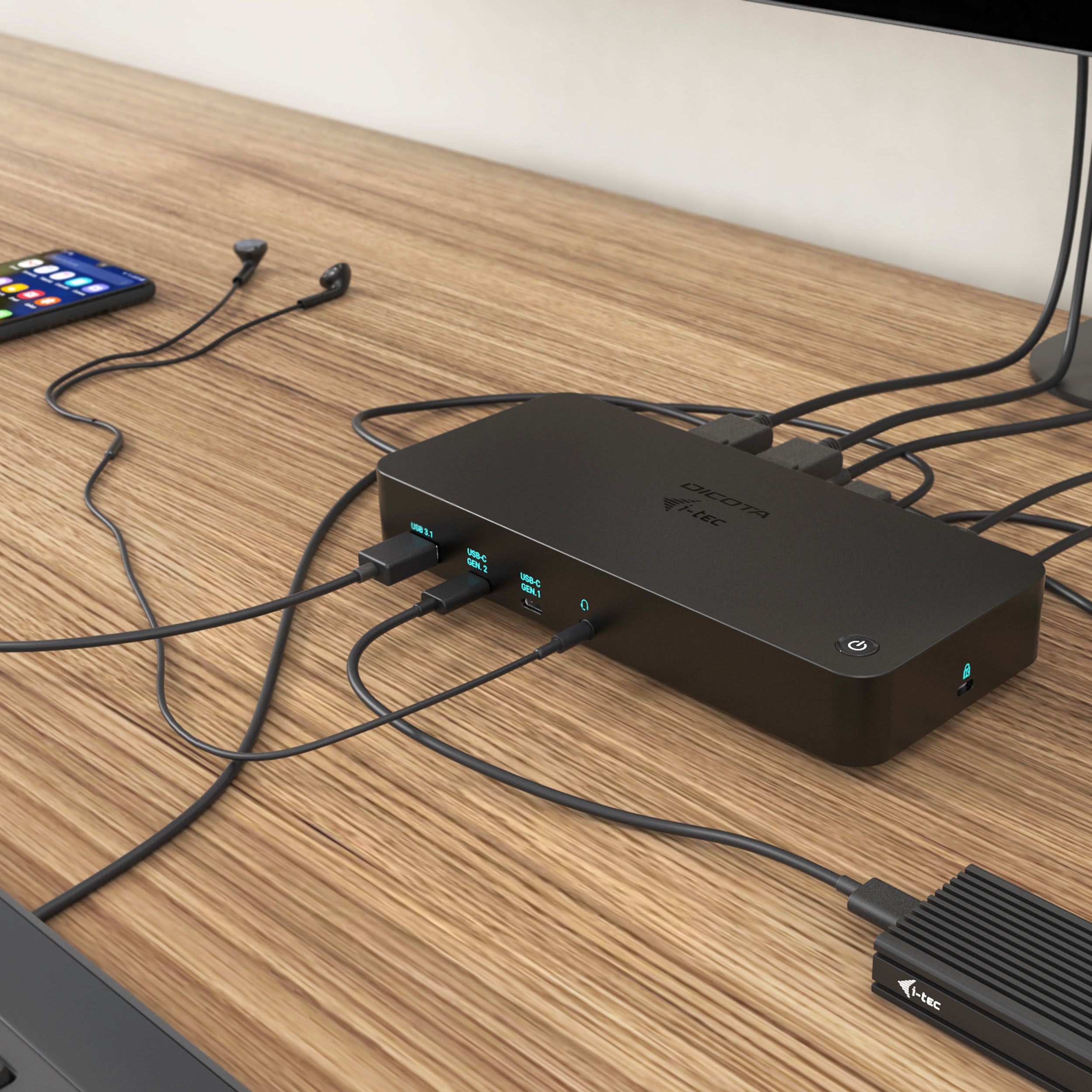 Ein schwarzer Hub mit mehreren Anschlüssen auf einem Holzschreibtisch. Ein Telefon, Kopfhörer und Kabel sind angeschlossen.
