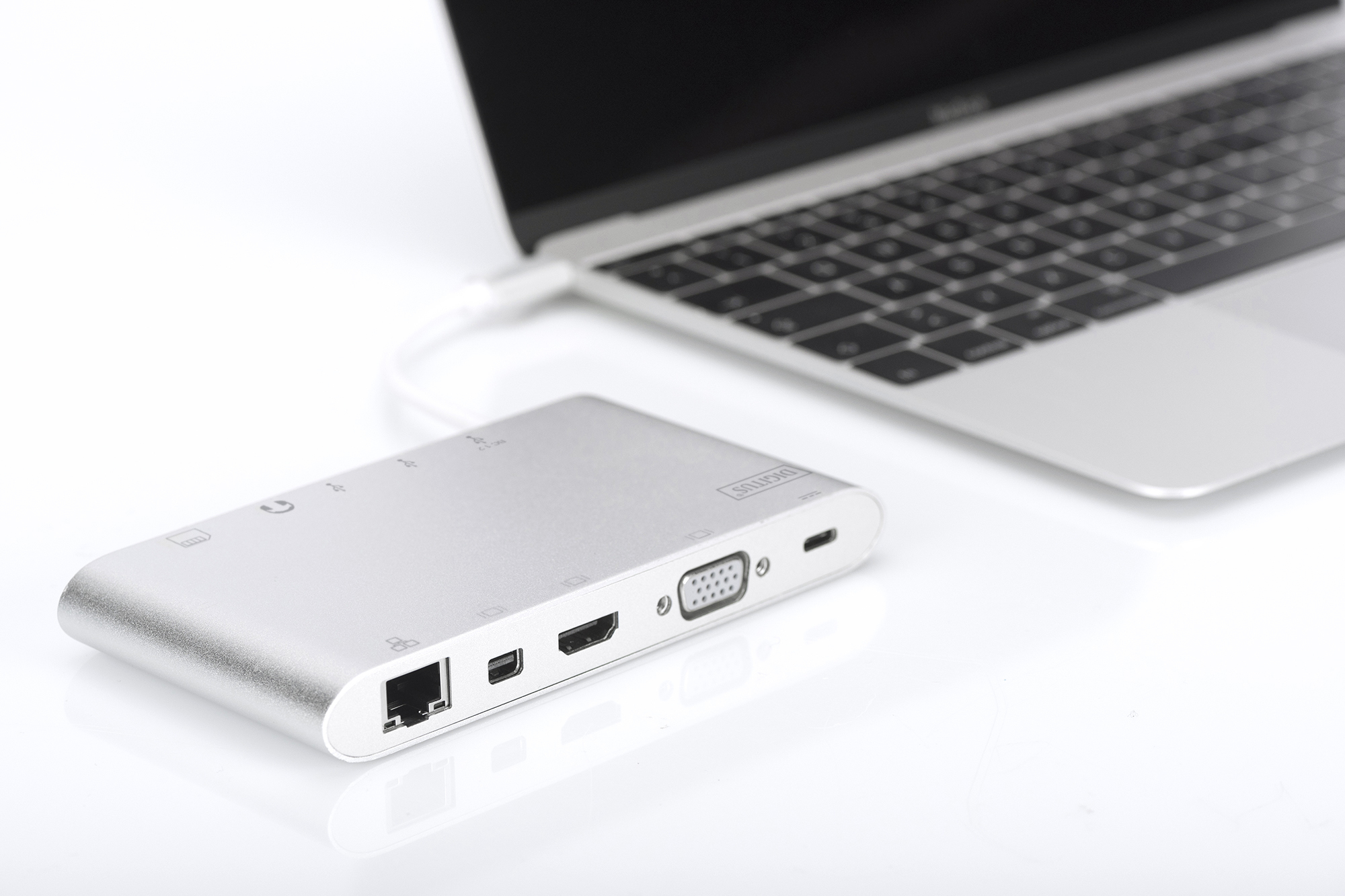 Un hub argentato collegato a un laptop con un cavo bianco, su sfondo bianco.