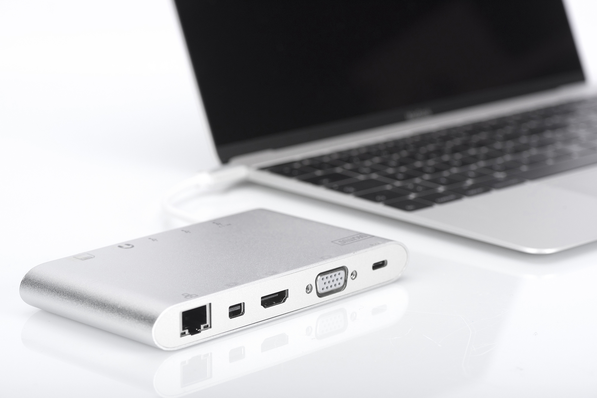 Laptop collegato a un hub USB argentato. Sfondo bianco.