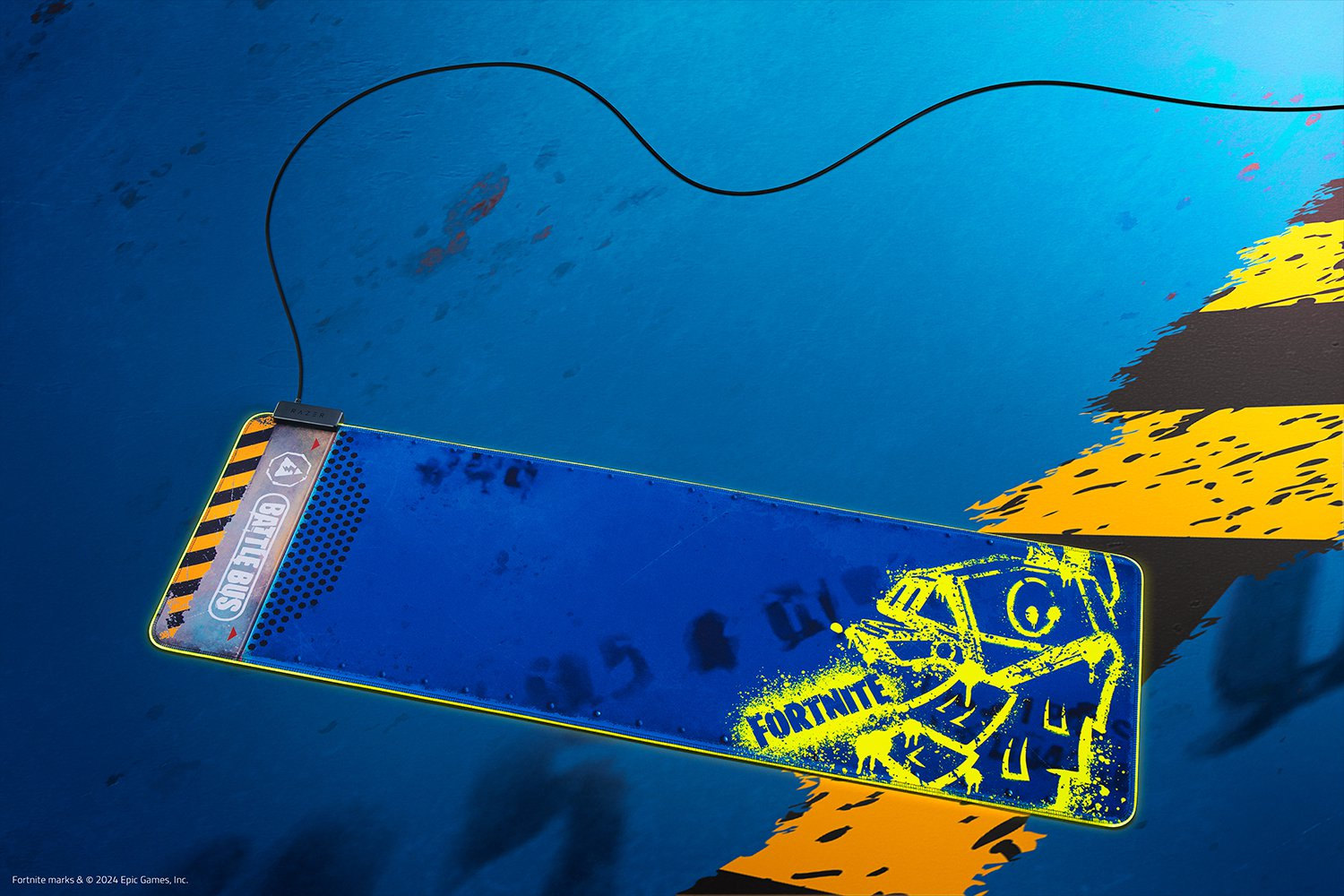 Niebiesko-żółta podkładka pod mysz Fortnite z kablem. Ma logo 'Battle Bus'.