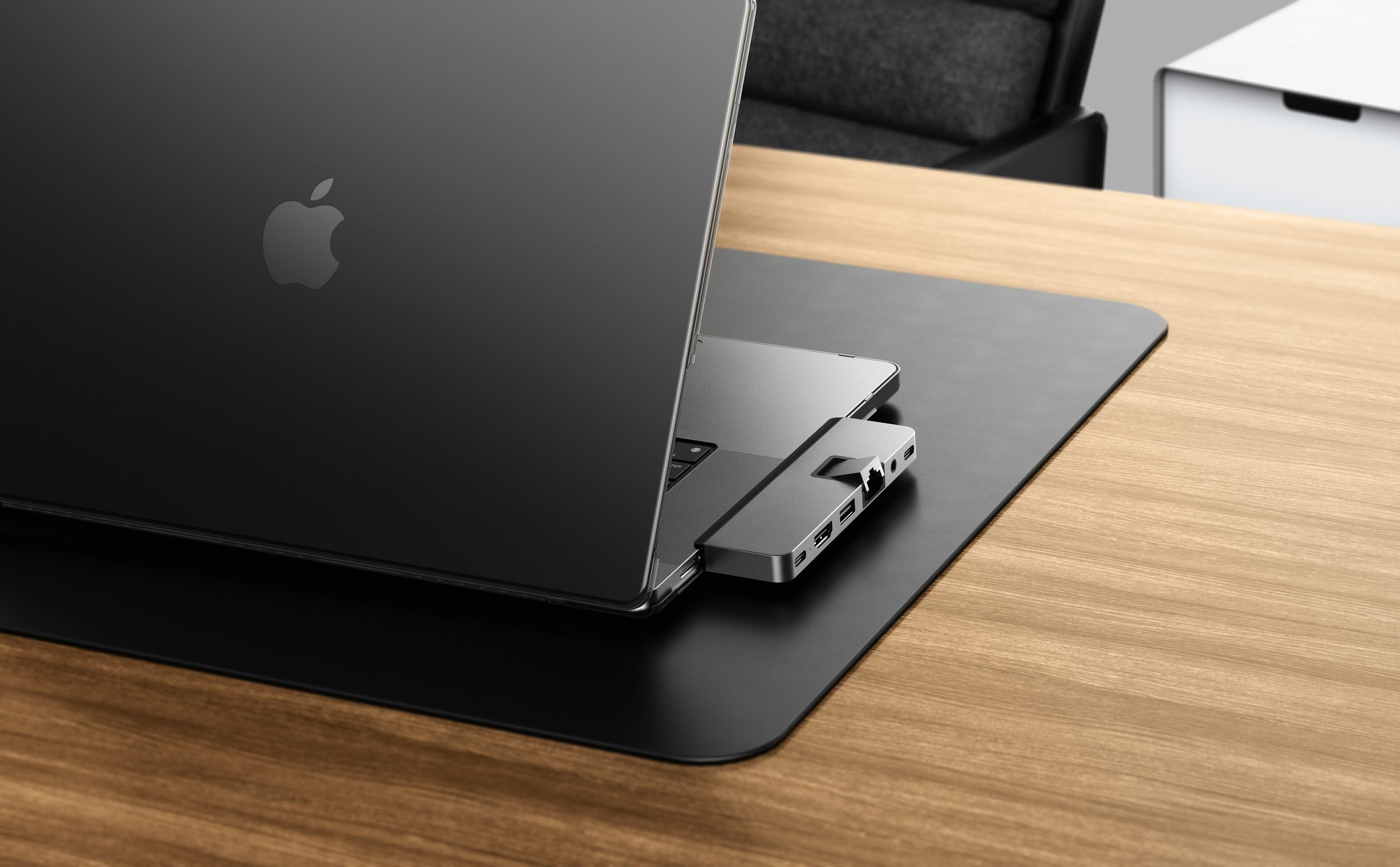 Laptop en un escritorio de madera con un concentrador conectado. Alfombrilla negra.