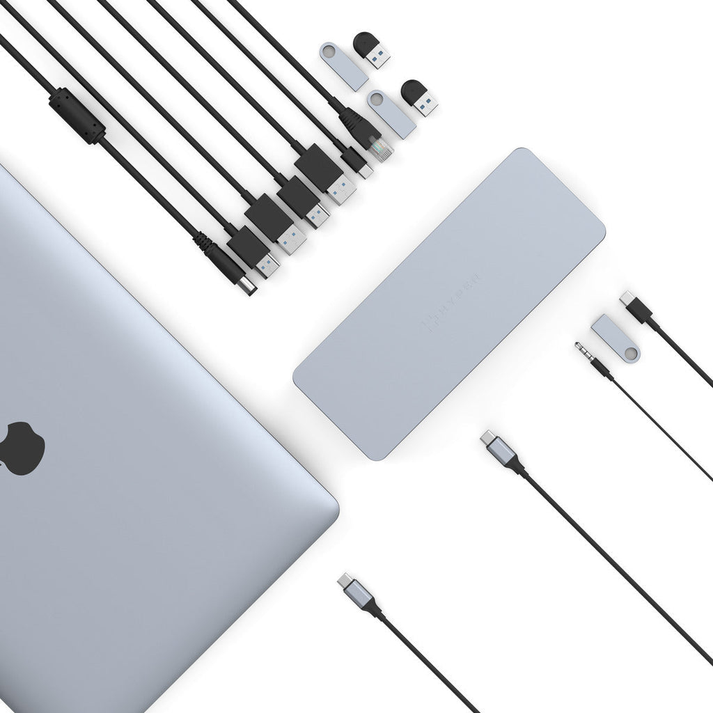 Ordenador portátil, estación de acoplamiento y accesorios como unidades USB y cables sobre fondo blanco.