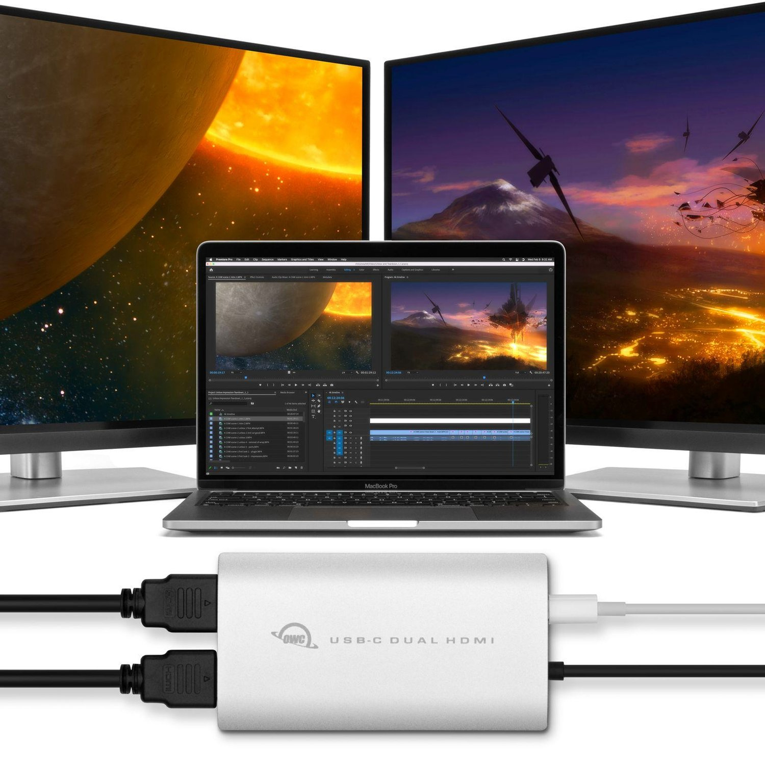 Laptop met bewerkingssoftware tussen twee monitoren met ruimtescènes. Zilveren USB-hub.