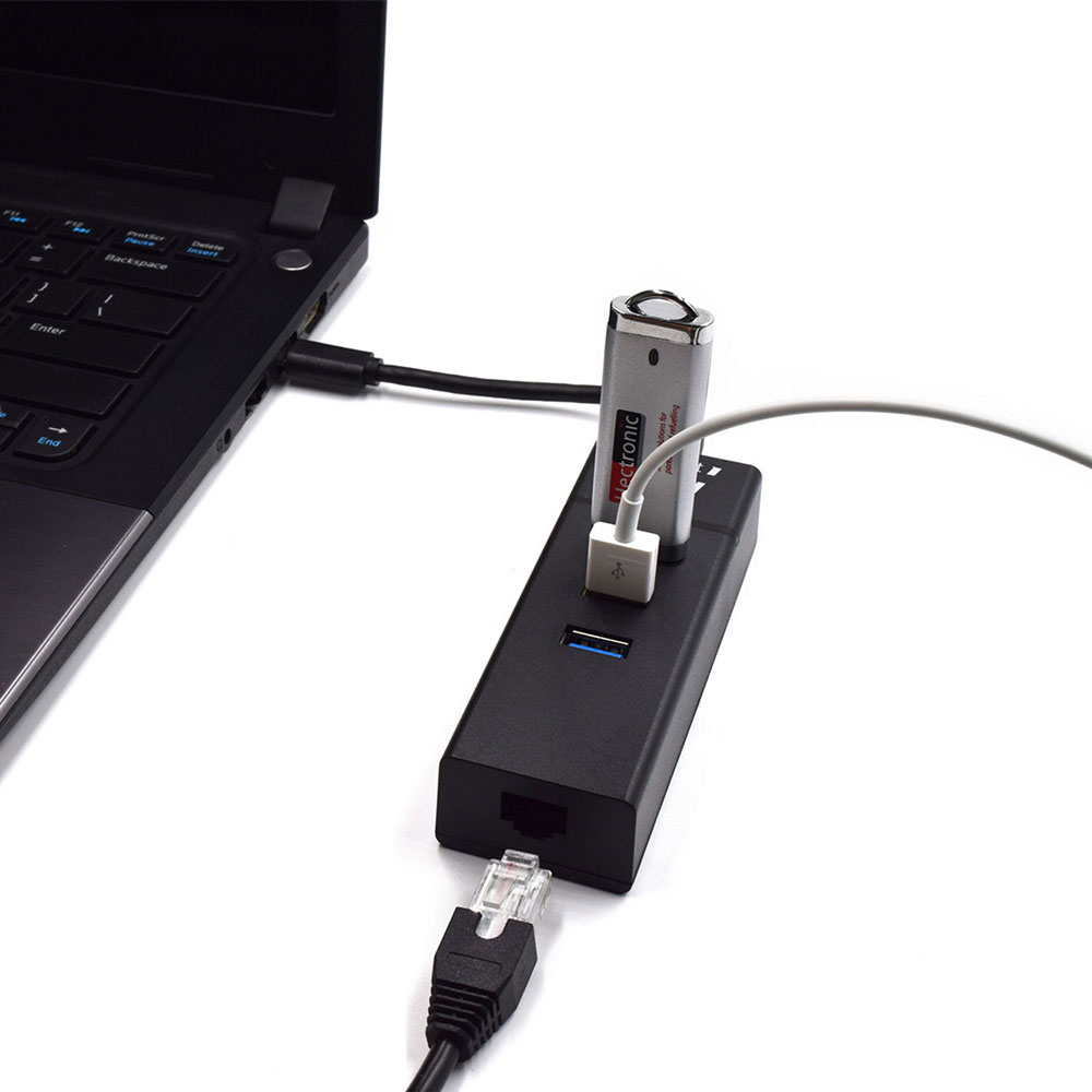Un portátil conectado a un concentrador USB negro con una unidad flash y un cable enchufado.