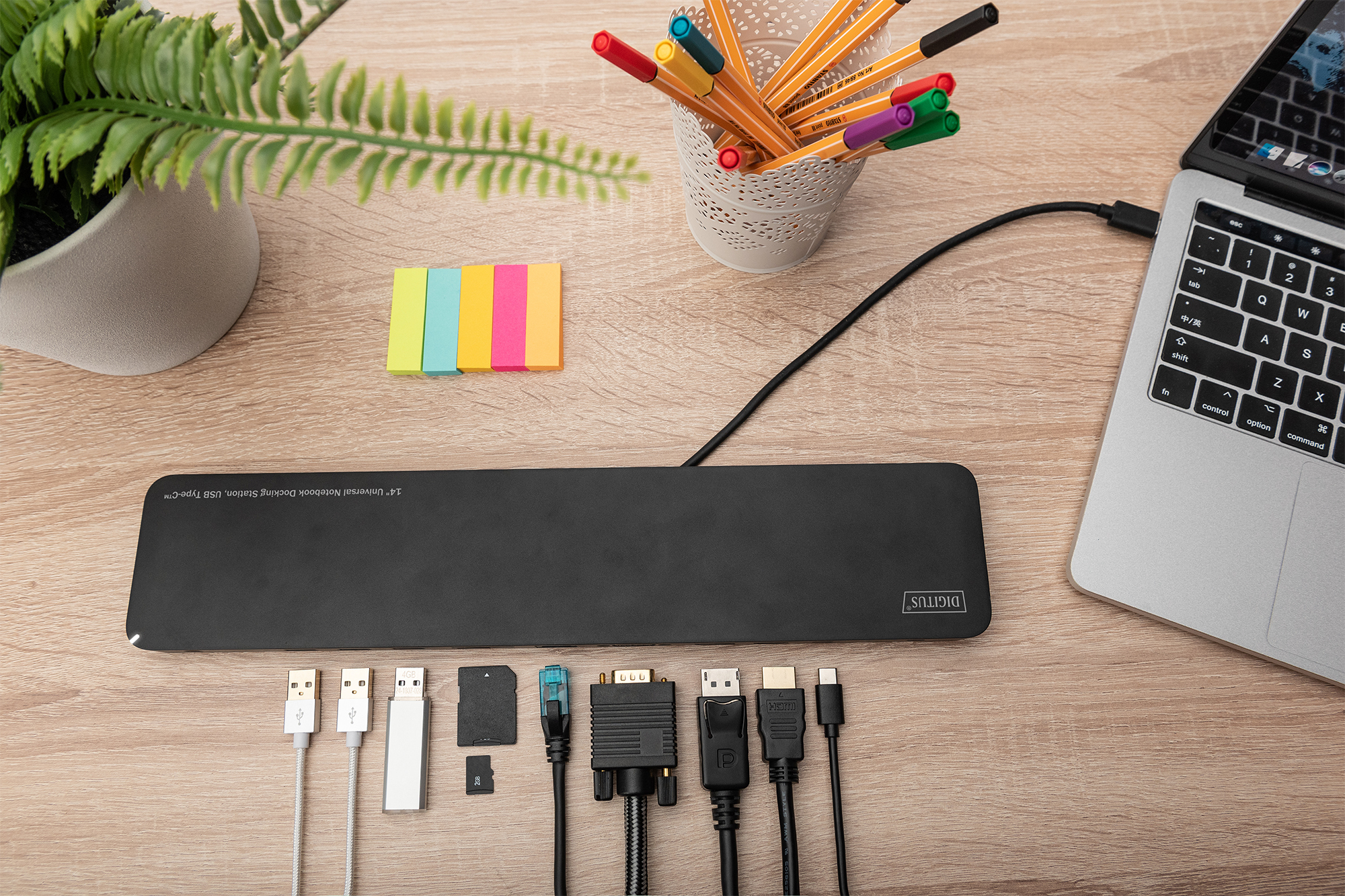 Schreibtisch mit Laptop, USB-Hub, Haftnotizen, Stiften und verschiedenen Anschlüssen.
