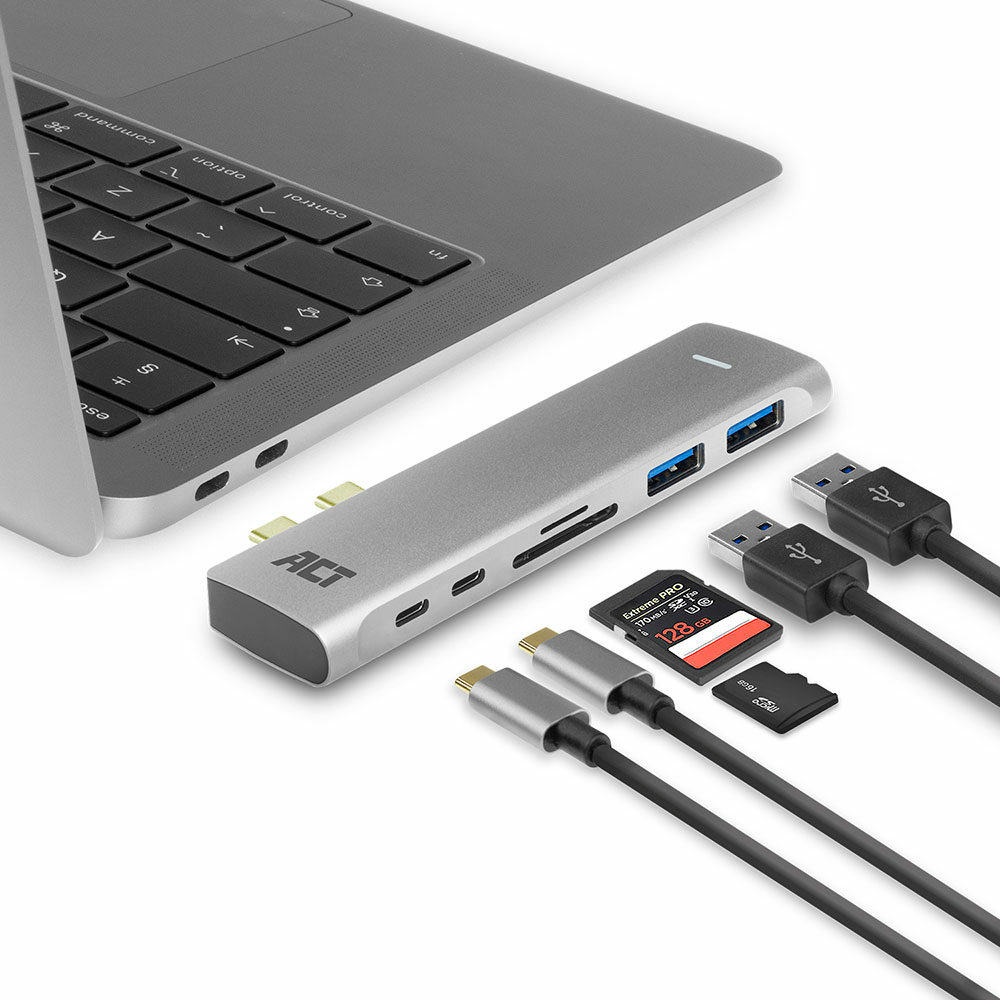 Hub argentato con porte USB, lettore di schede SD e cavi USB collegati a un laptop.