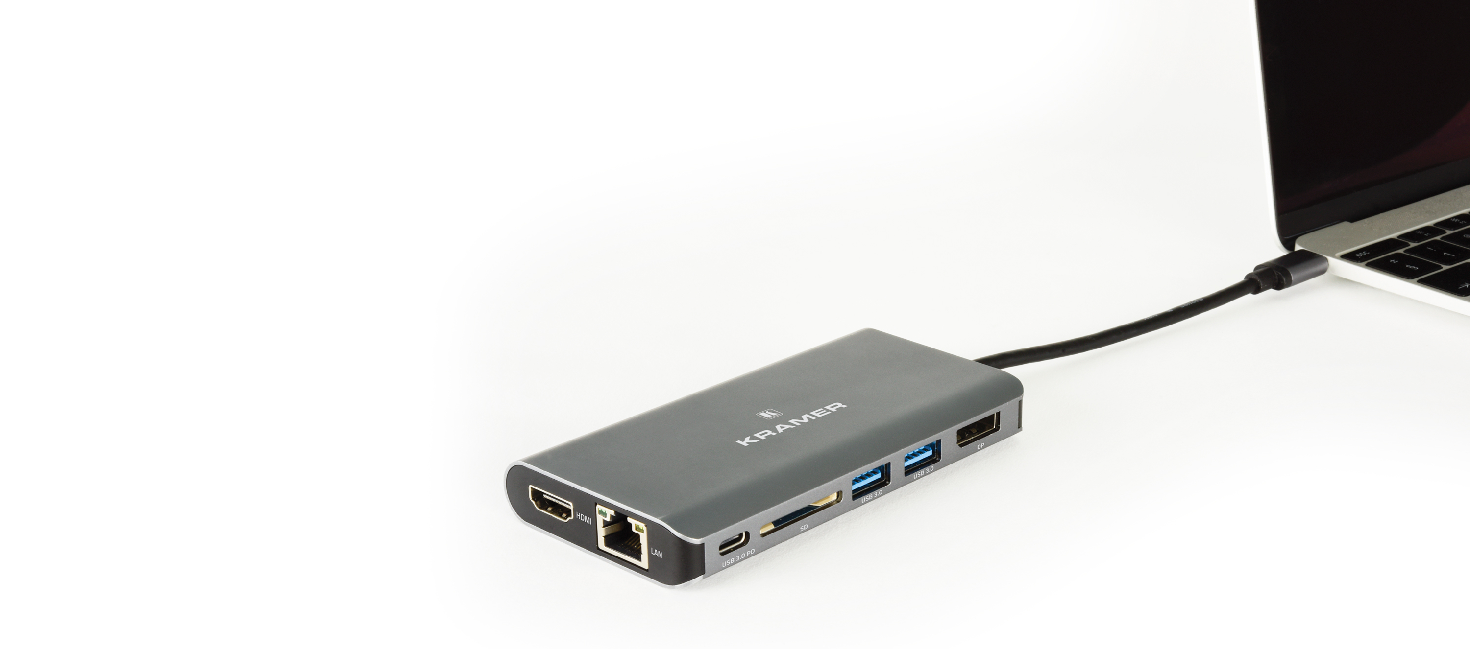 Un hub USB grigio collegato a un laptop su sfondo bianco.