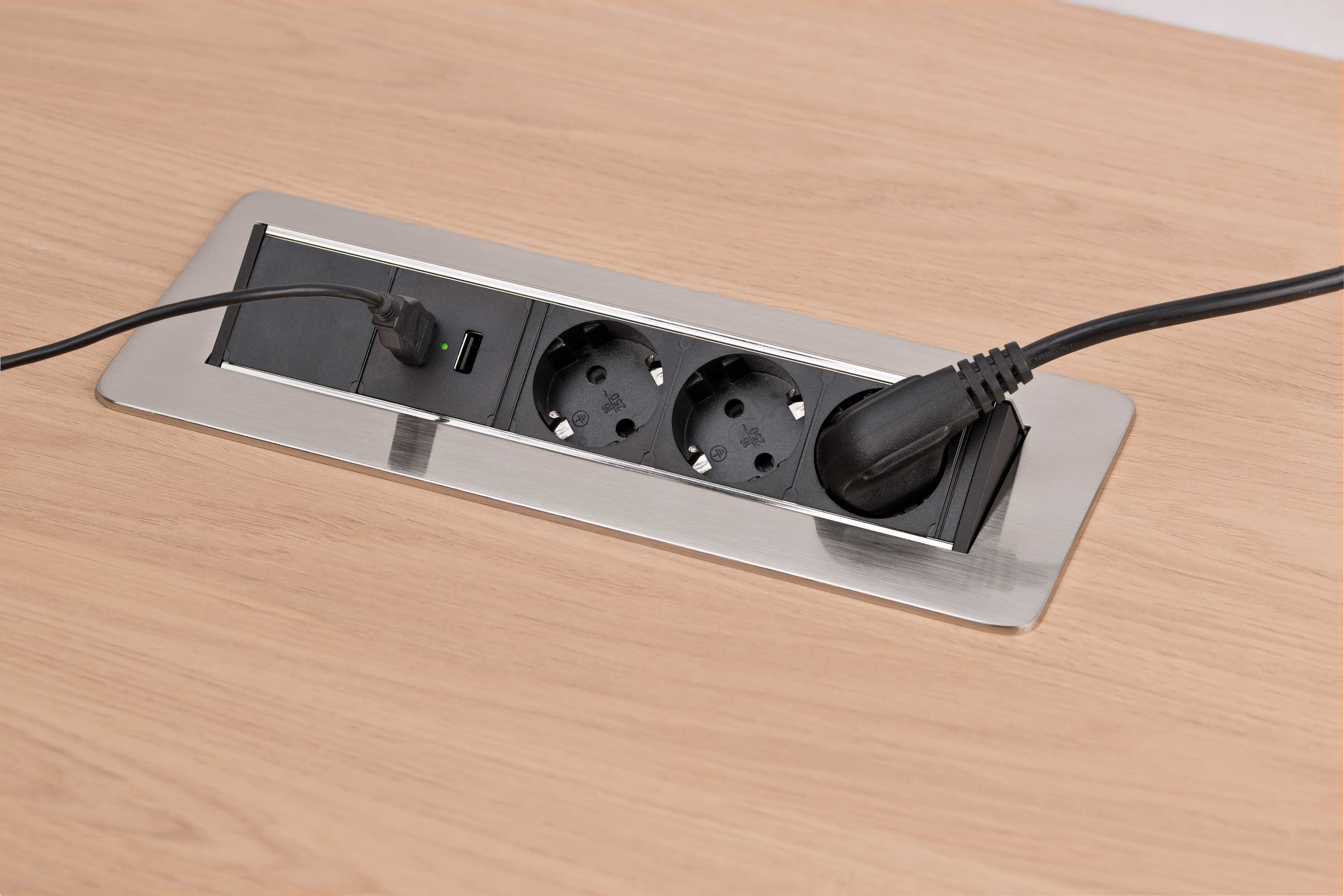 Presa di corrente incastonata nel legno. Tre prese di corrente e una porta USB. Cornice in acciaio inossidabile. Tavolo di legno.