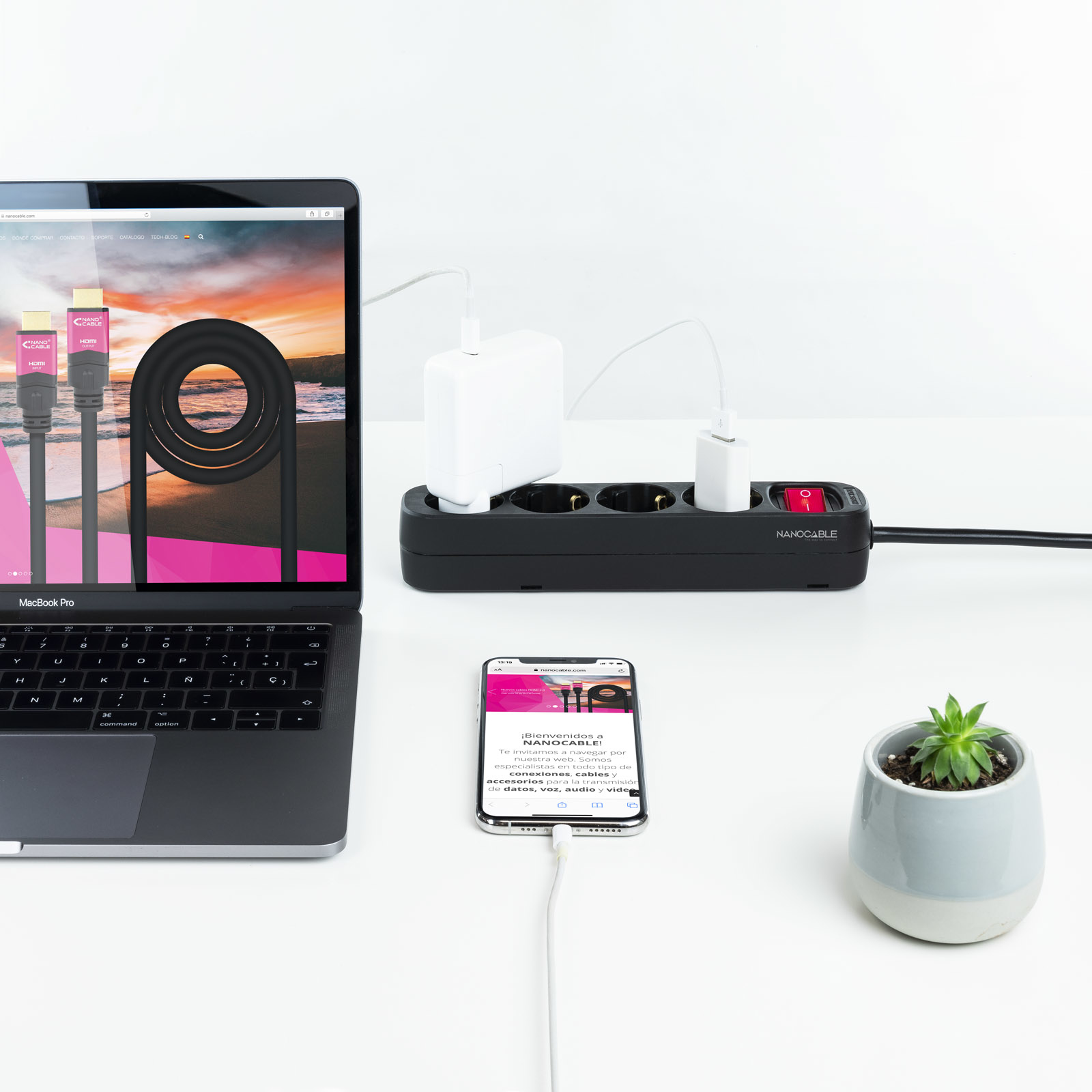 Laptop, smartfon i listwa zasilająca z wieloma urządzeniami ładującymi się.