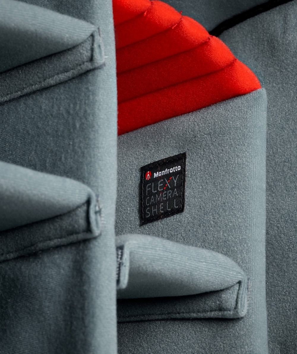 Innenraum der Kameratasche. Grauer Stoff mit roter Polsterung. Manfrotto-Logo. Schutzdesign.