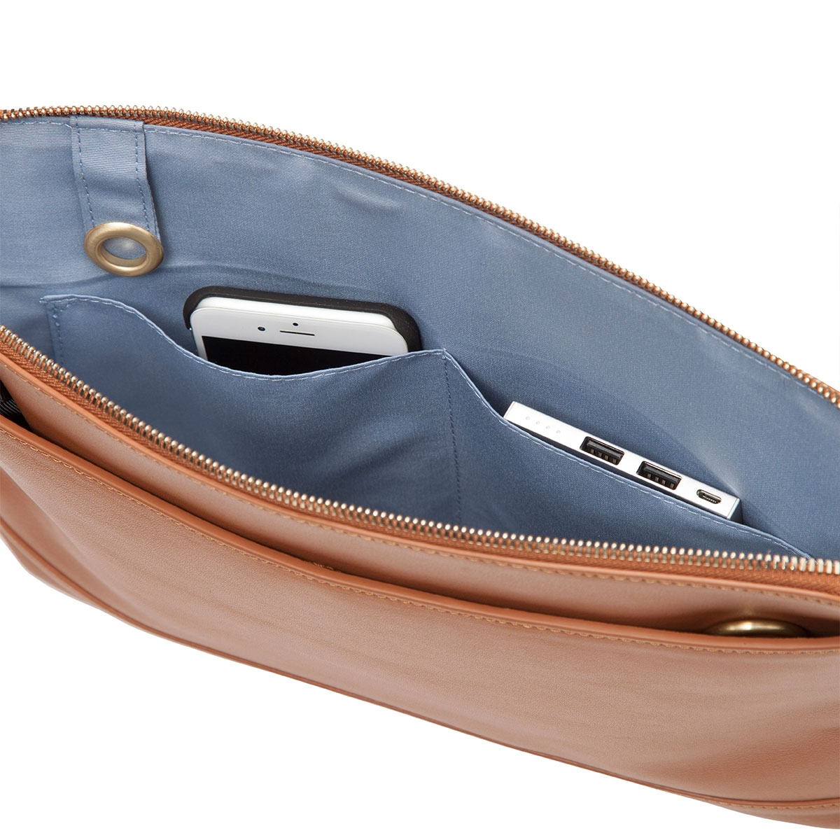 Otwarta brązowa skórzana torba z telefonem, power bankiem i niebieską podszewką.