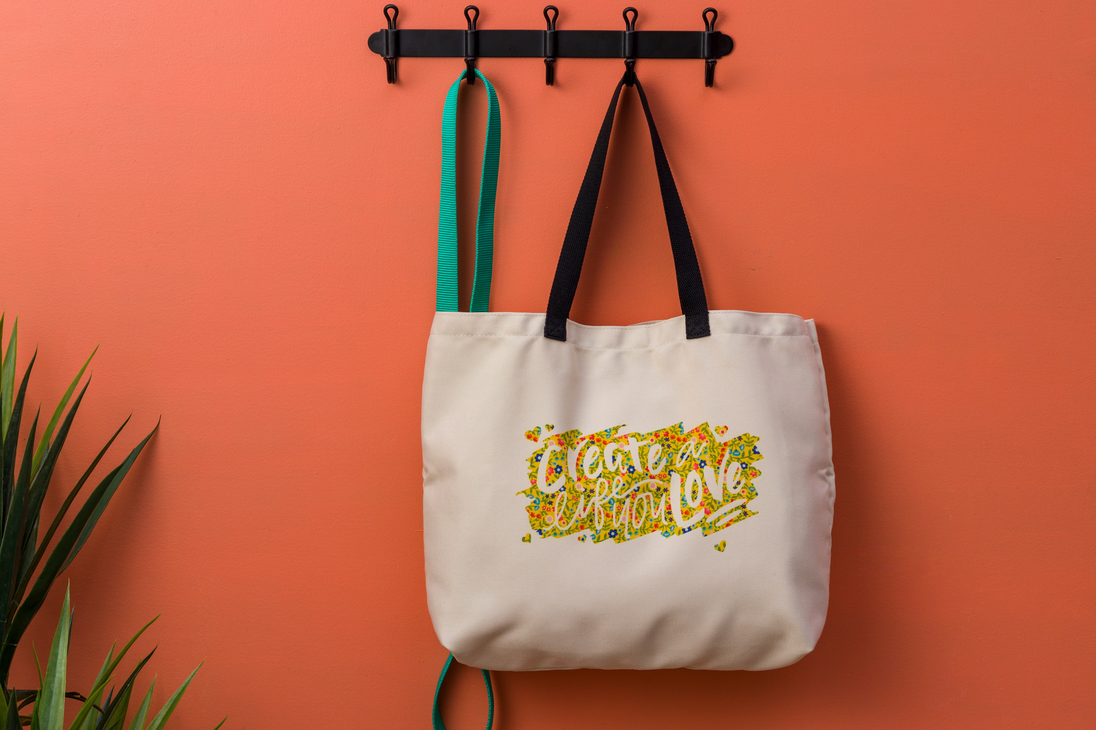 Eine cremefarbene Tragetasche mit einem bunten Blumendesign und dem Schriftzug 'create a life you love'.