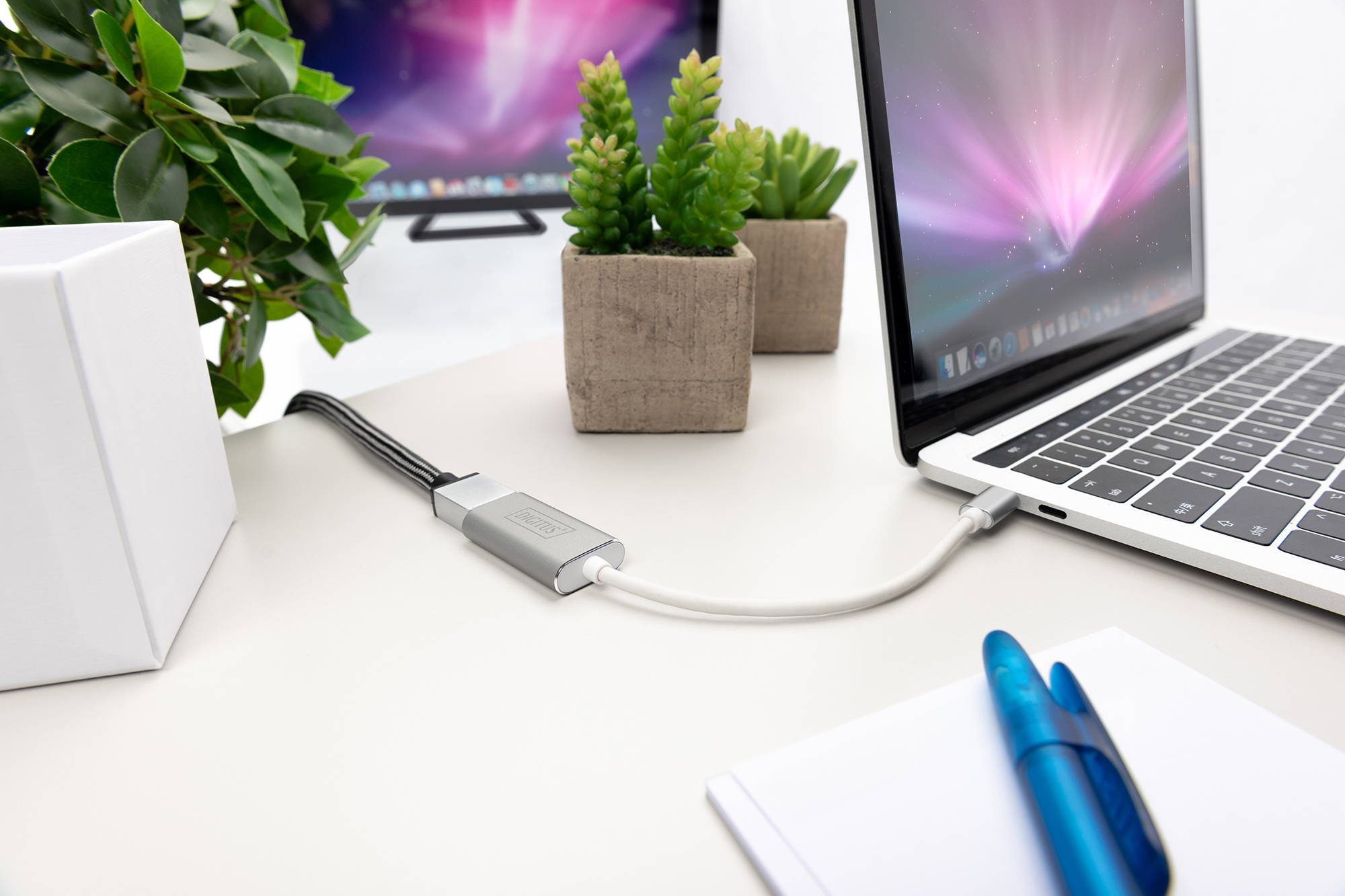 Laptop, der mit einem silbernen Adapter und einem weißen Kabel verbunden ist. Weißer Hintergrund.