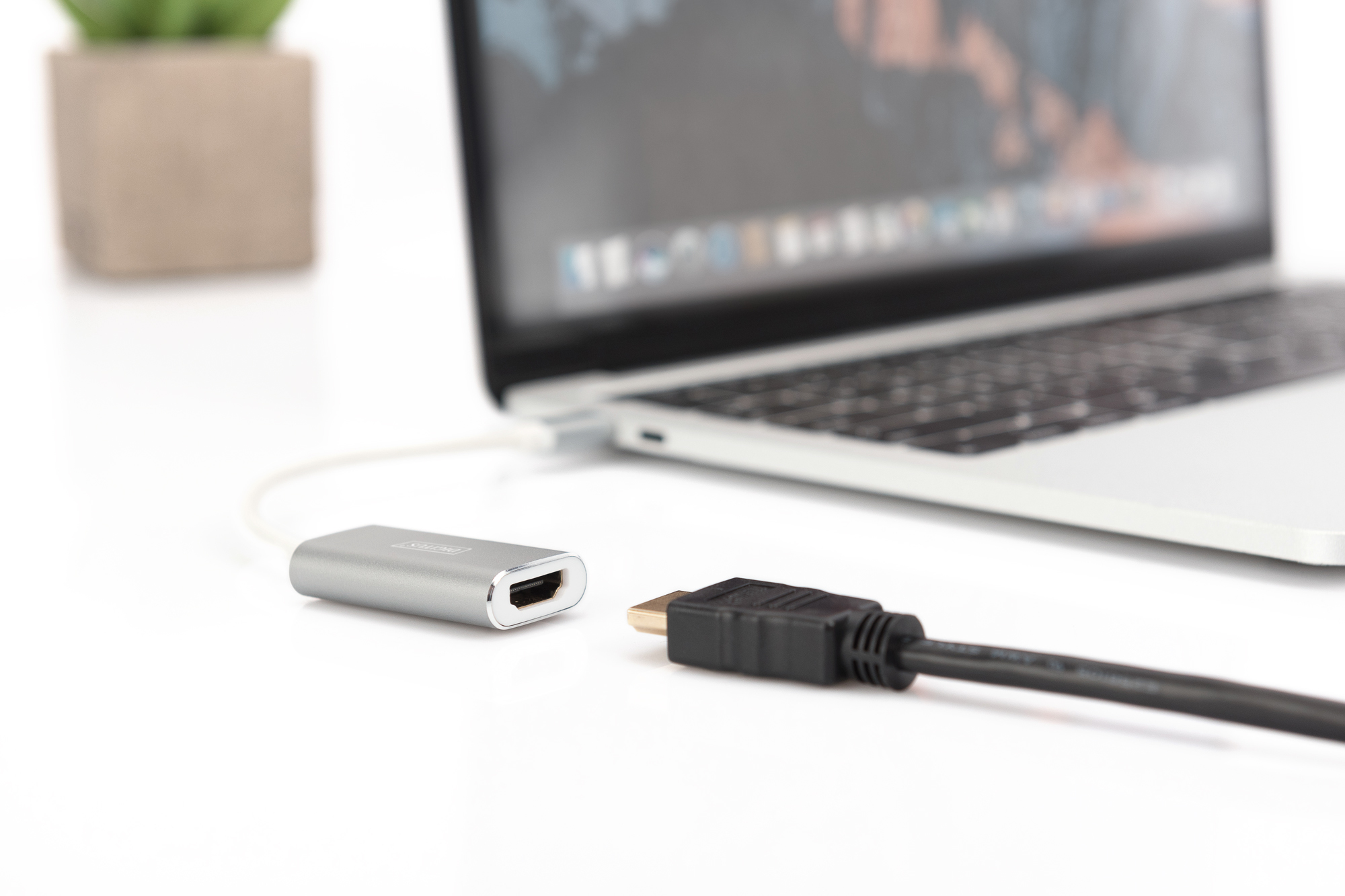 Laptop mit HDMI-Adapter und Kabel. Silberner Adapter am Laptop, schwarzes HDMI-Kabel daneben.