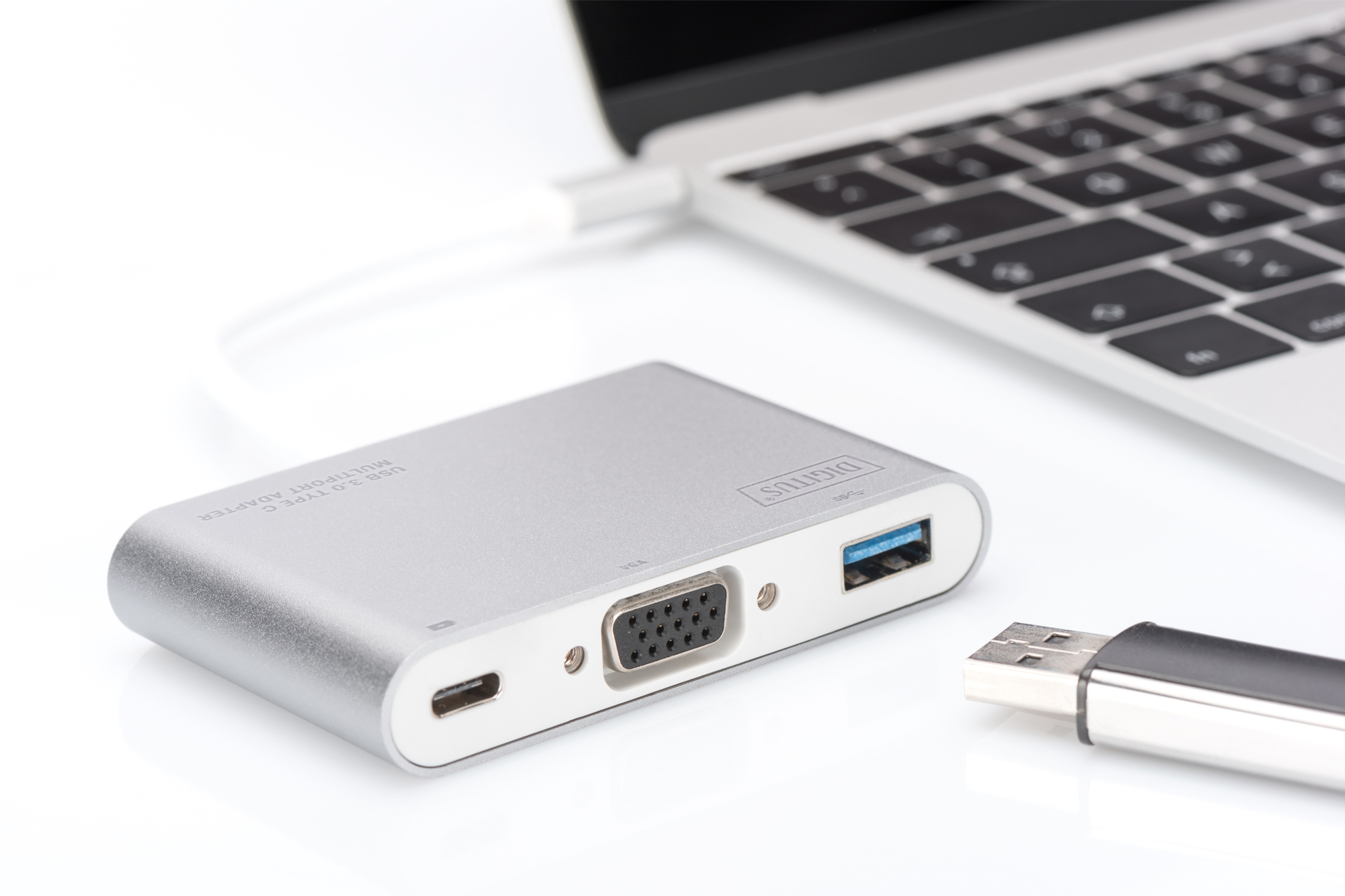Dizüstü bilgisayara bağlı gümüş renkli USB-C çoklu bağlantı noktası adaptörü. Sağda bir USB sürücü var.