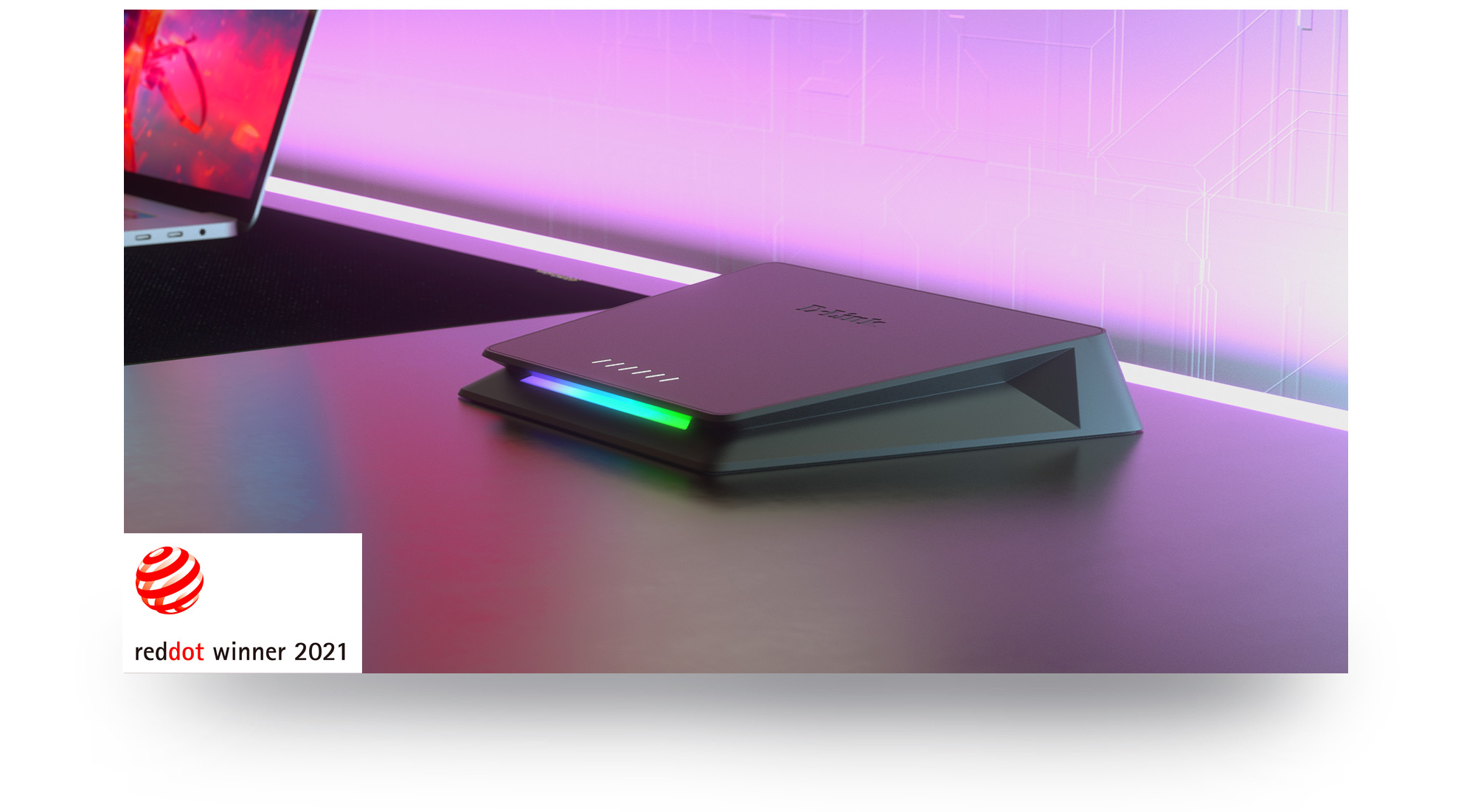 Czarny router z kolorowymi światłami na stole. Laptop częściowo widoczny w tle.