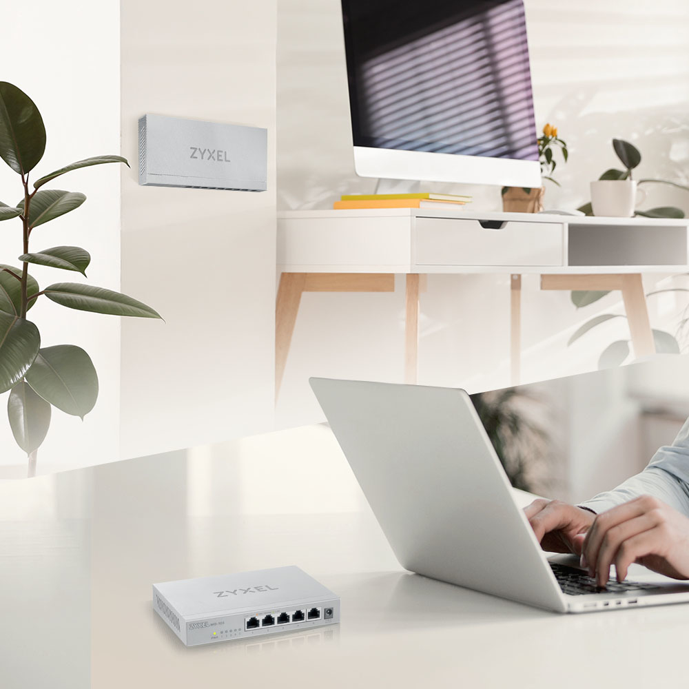 Osoba używająca laptopa w pobliżu przełącznika Zyxel zamontowanego na ścianie. Obecny jest komputer.