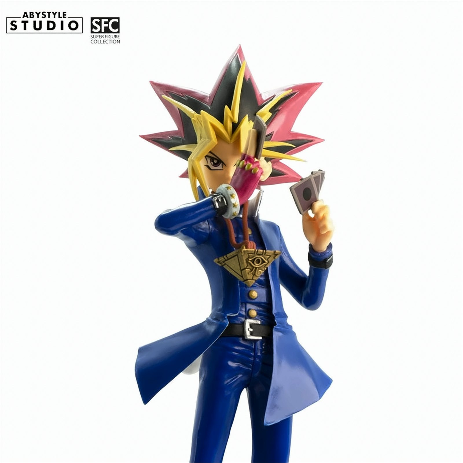 Eine Yugi Muto Figur in blauem Mantel, Karten haltend, auf weißem Hintergrund.