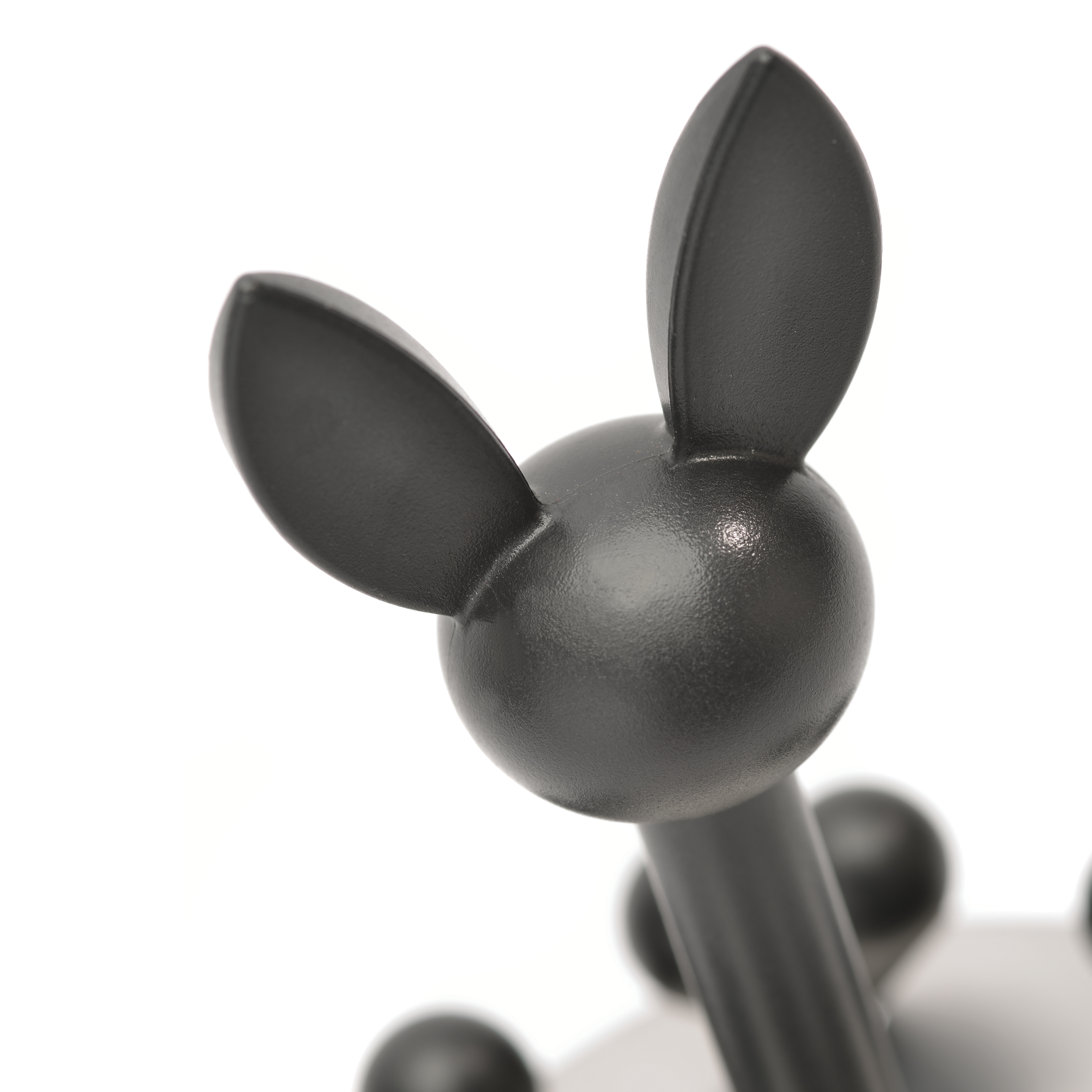 Close up of black coat hooks in the shape of a bunny head. The hooks are on a white background.