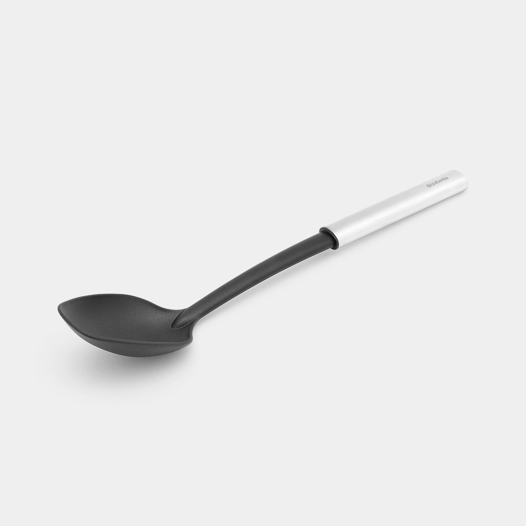 Cucchiaio da cucina nero e argento su sfondo bianco.