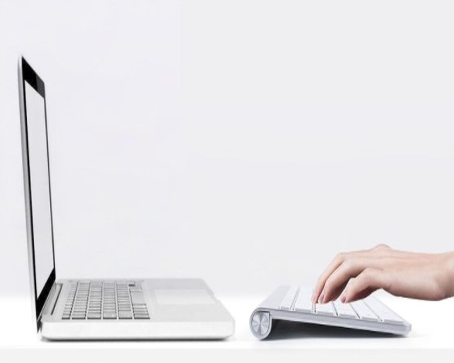 Laptop i klawiatura, osoba pisząca na klawiaturze.