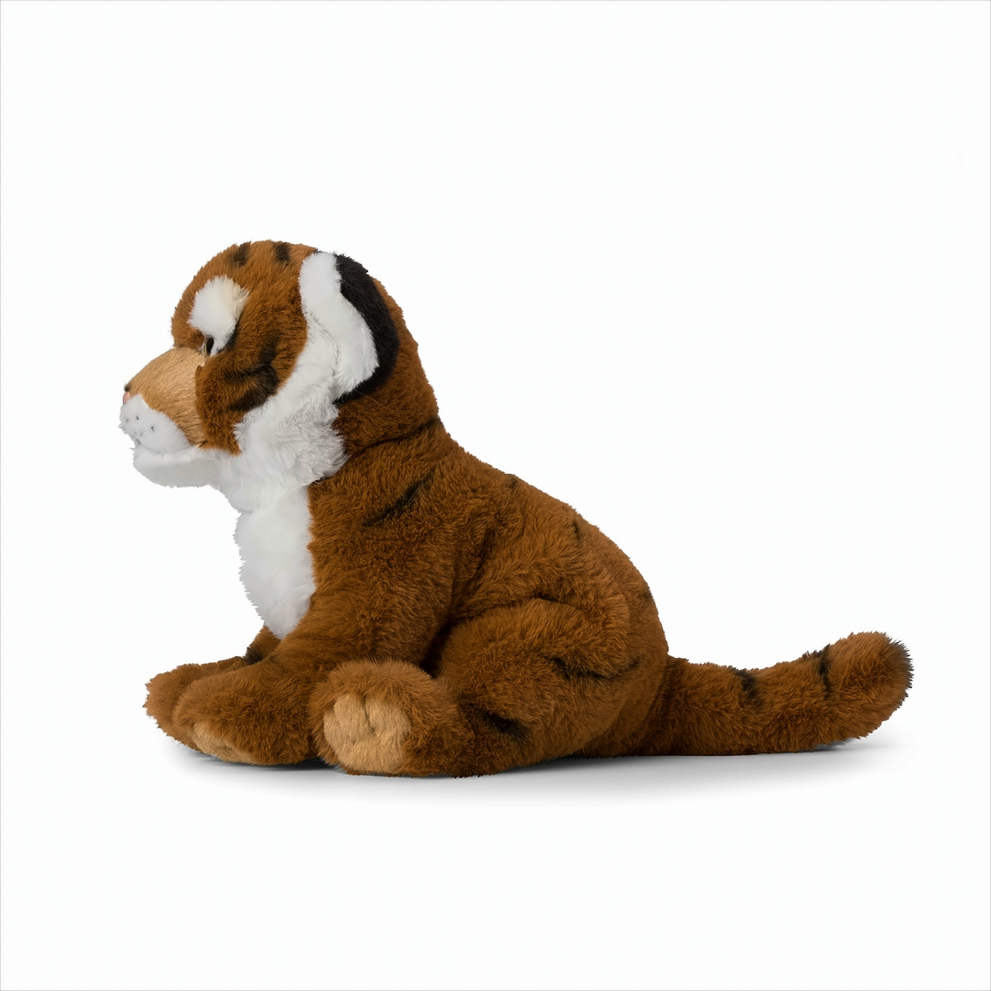 Tigre en peluche, marron et blanc, assis sur une surface blanche.