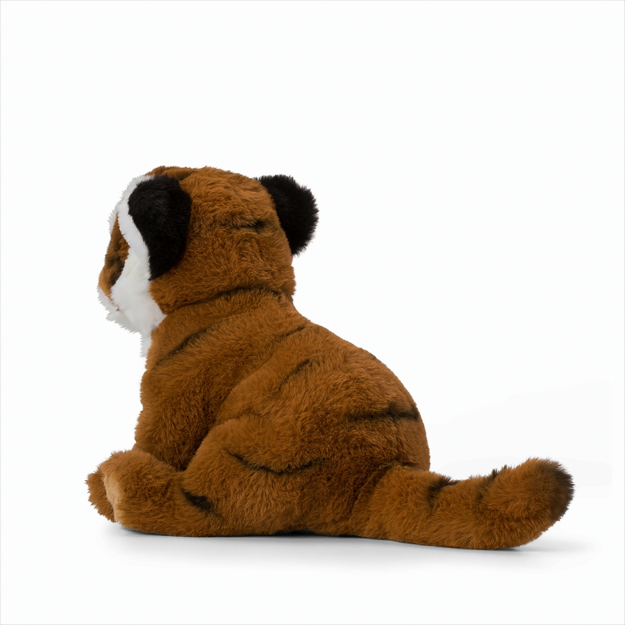 Une peluche de bébé tigre, marron avec des rayures noires, assise sur une surface blanche. Vue de côté.