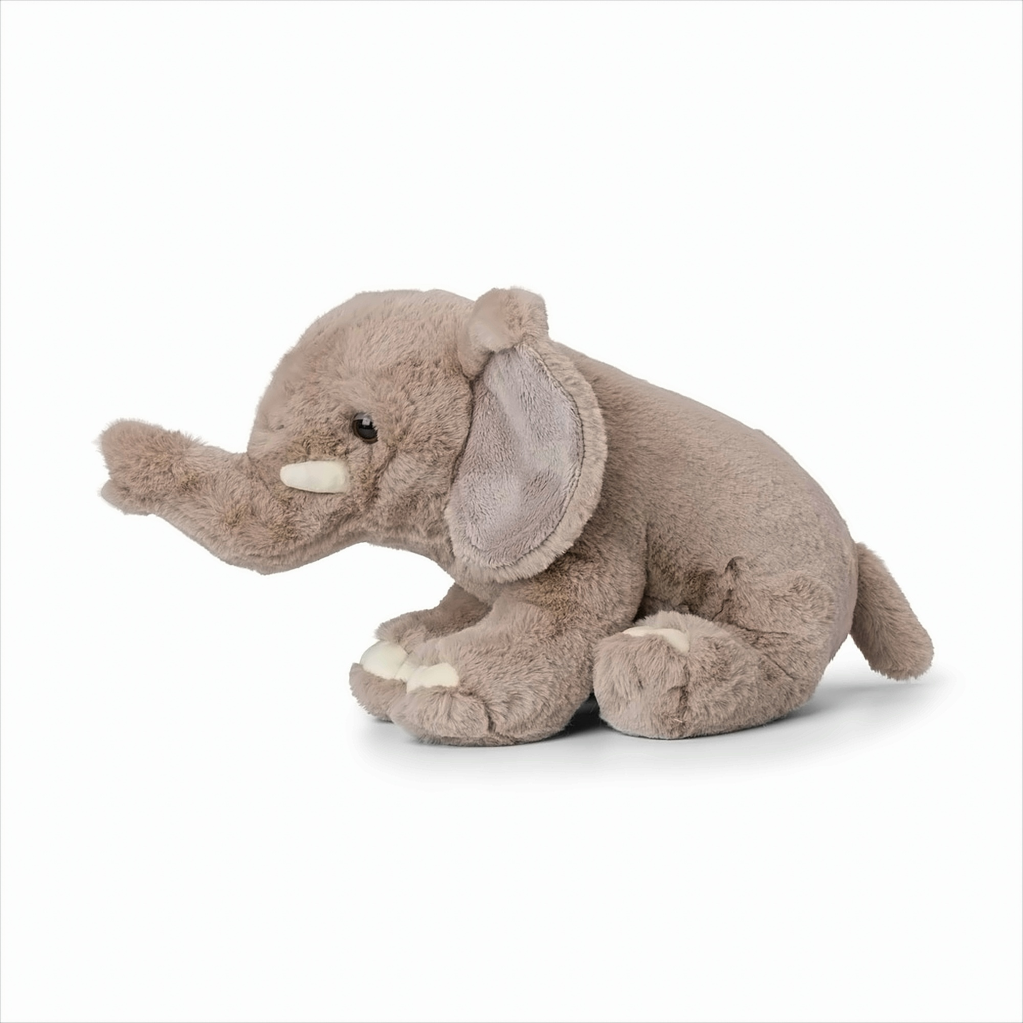 Un éléphant en peluche gris sur une surface blanche. Il est assis.