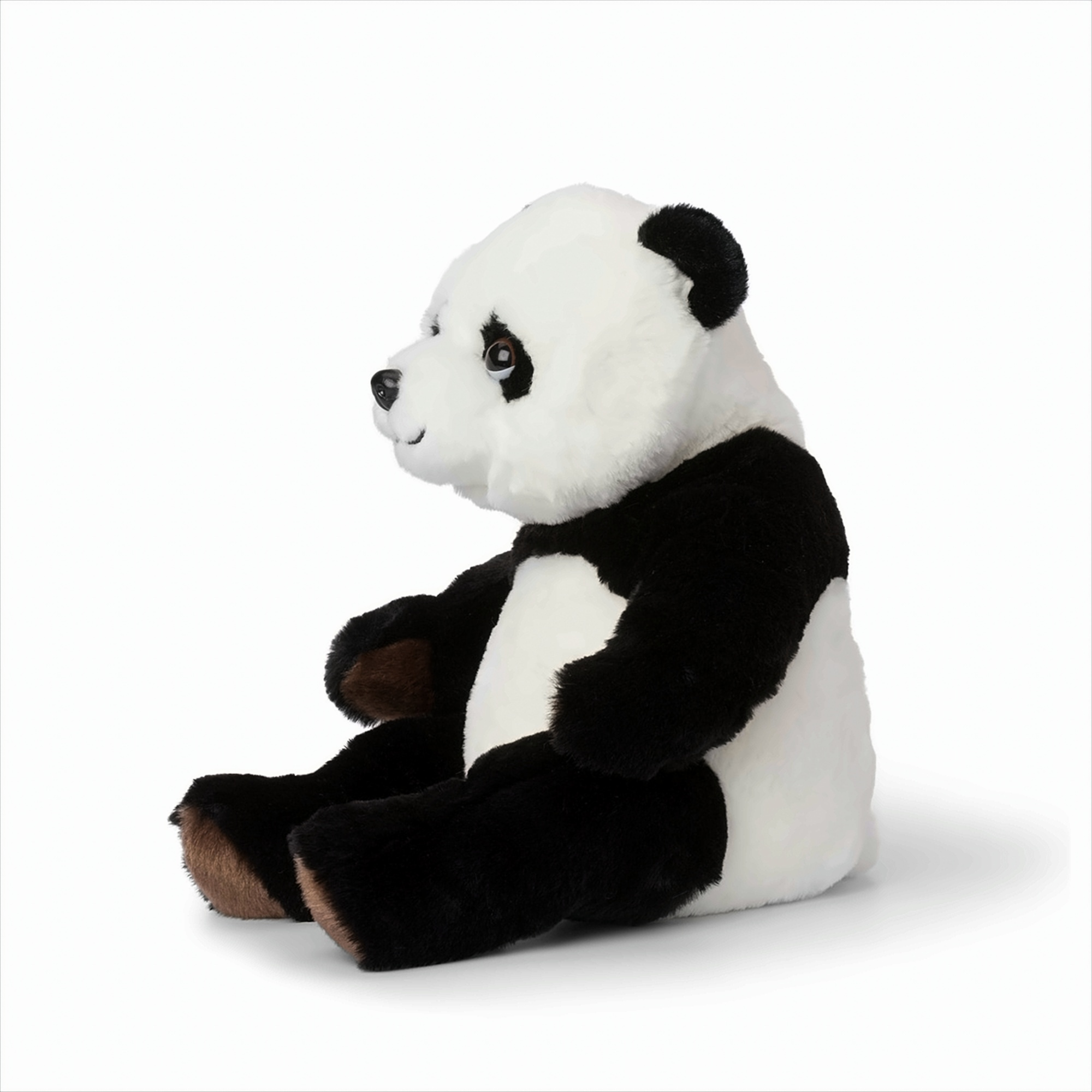 Peluche panda noir et blanc, assis, regardant à gauche sur fond blanc.