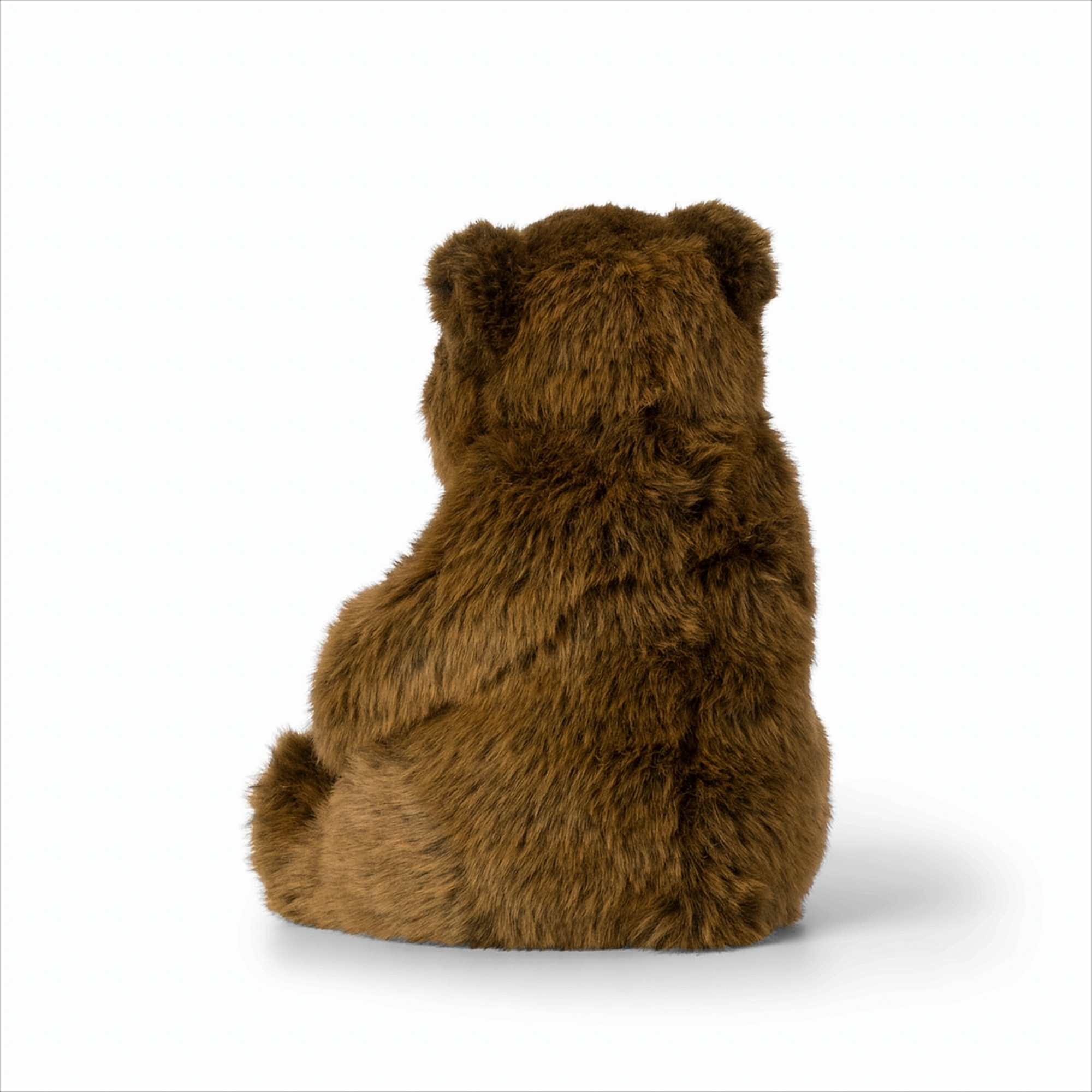 Ein Stofftierbär von hinten gesehen, auf einer weißen Oberfläche sitzend.