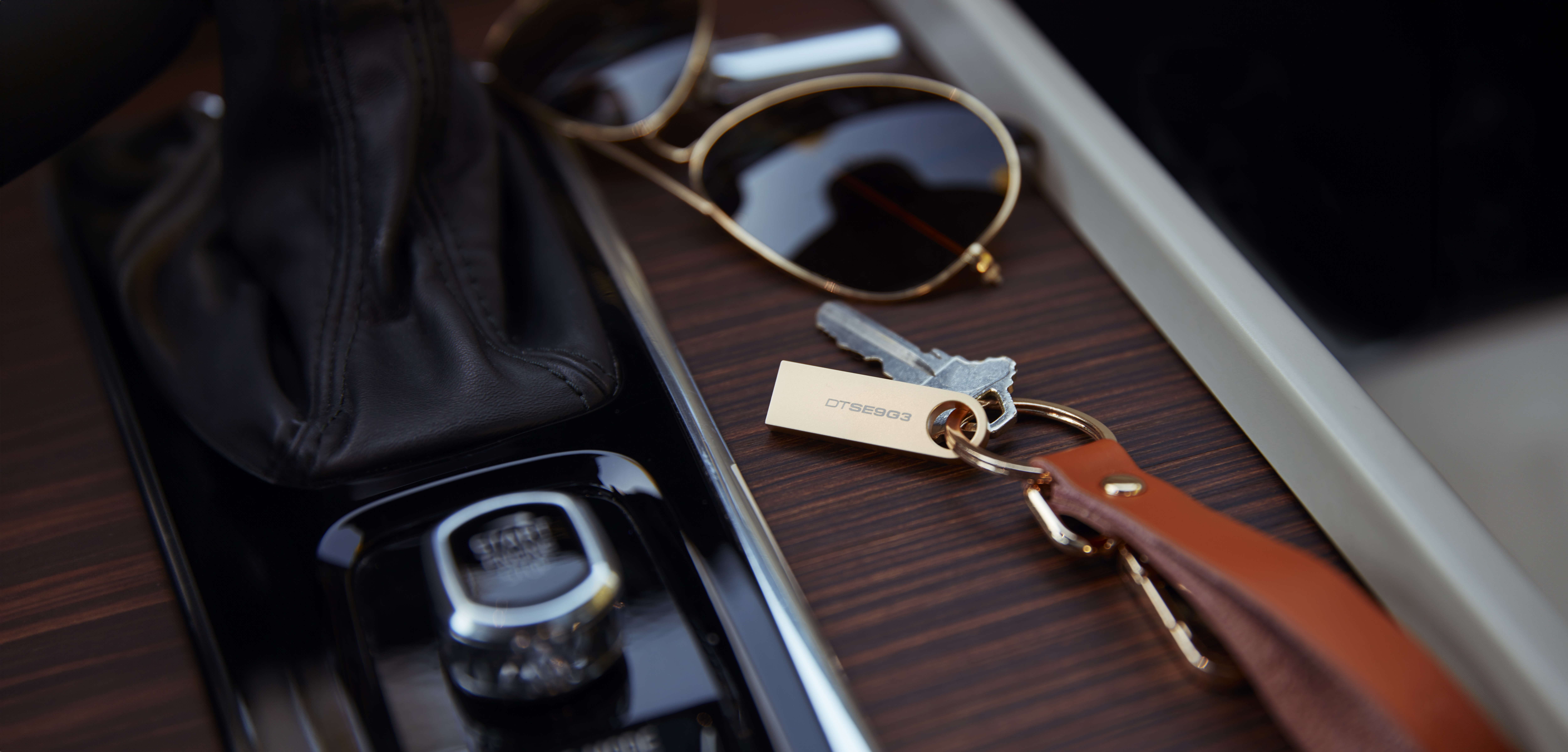 Klucze, okulary przeciwsłoneczne i detale wnętrza samochodu na drewnie.