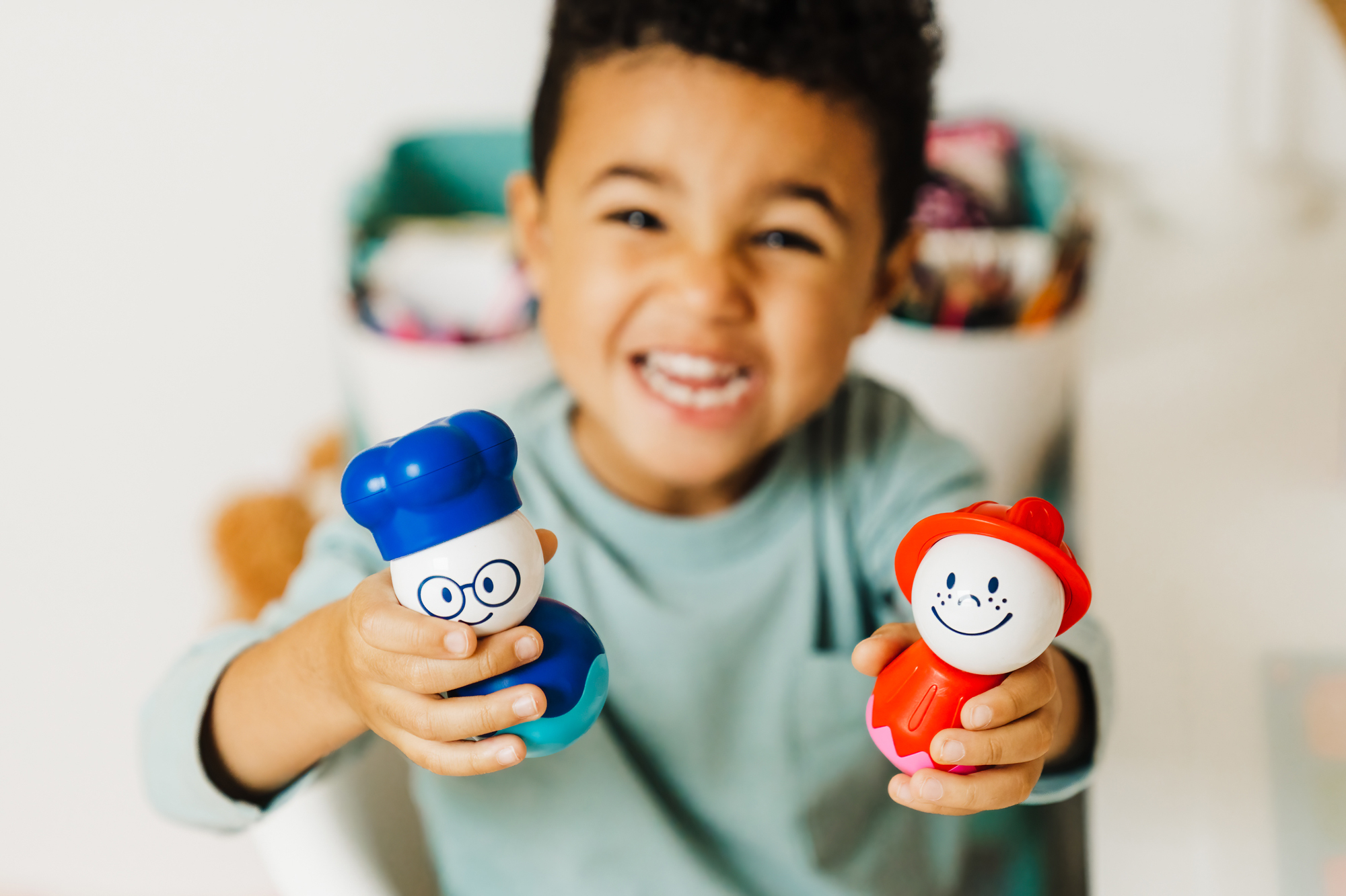 Un bambino che tiene due personaggi giocattolo, chef e pompiere.