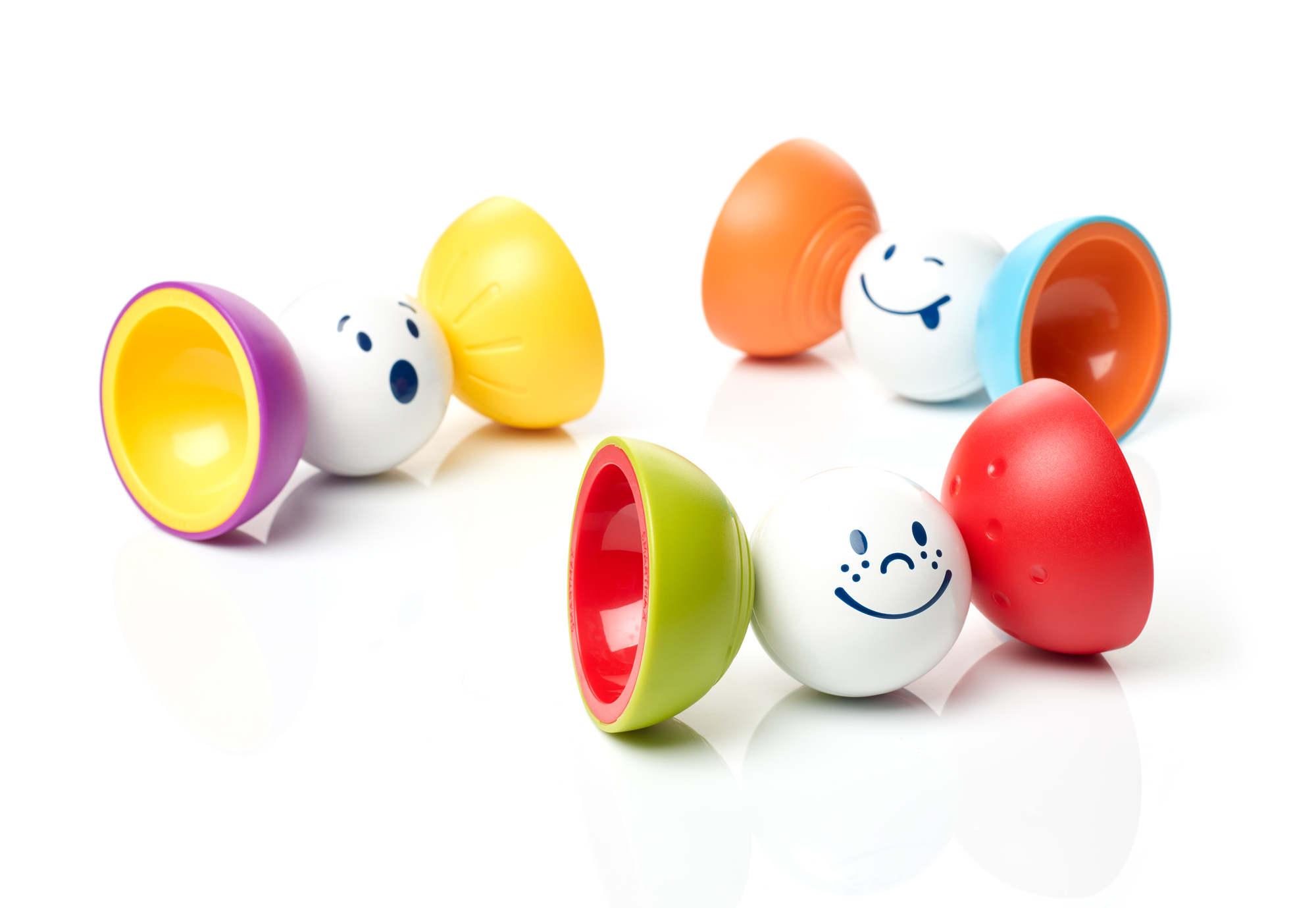Palline giocattolo colorate con facce sorridenti e gusci aperti, alcune collegate in fila.