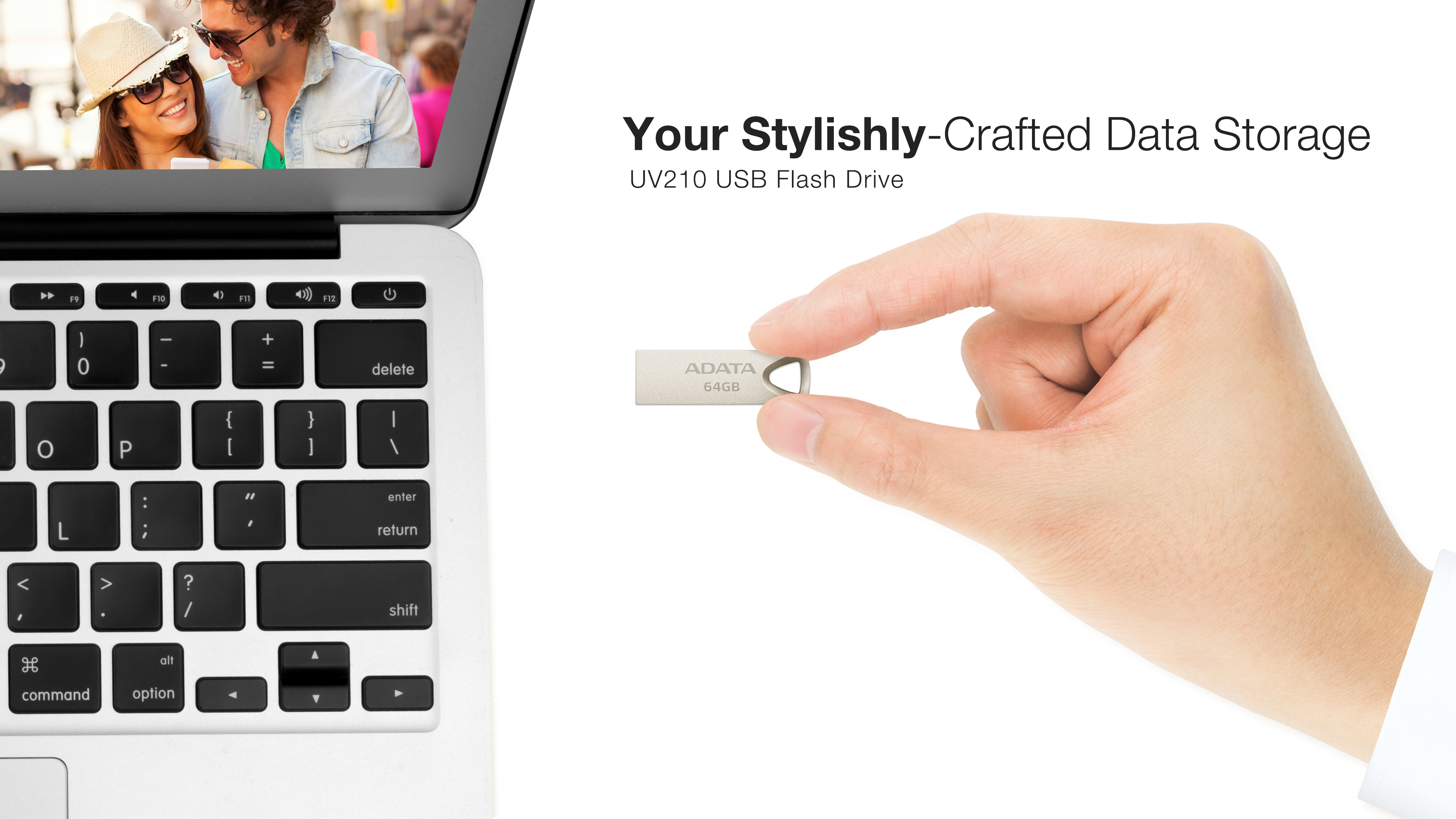 Ręka trzymająca srebrny pendrive ADATA w pobliżu laptopa z uśmiechniętą parą na ekranie.